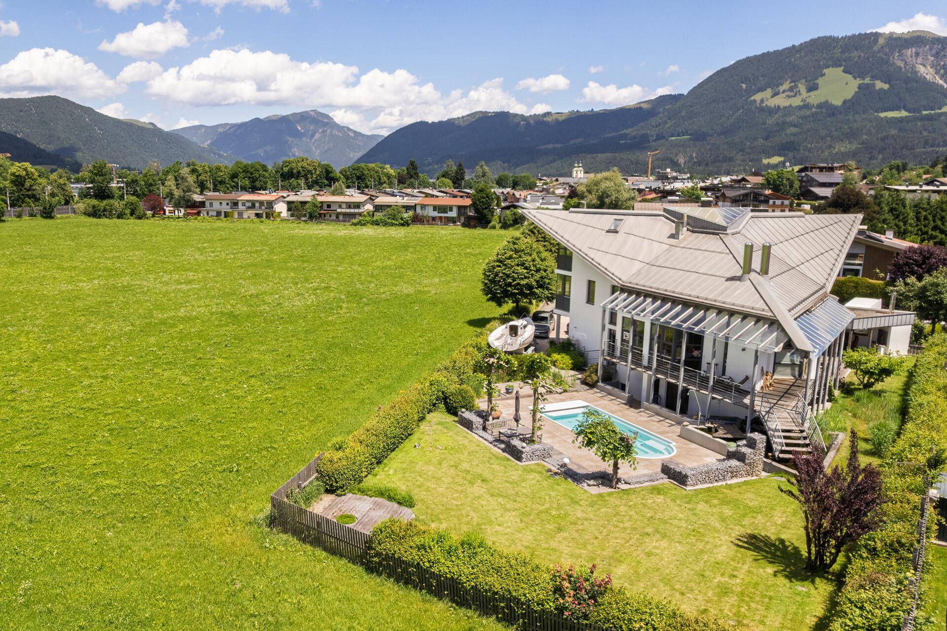 Weitläufige Luftaufnahme der Villa mit Pool, umgeben von grünen Feldern und einer kleinen Stadt.