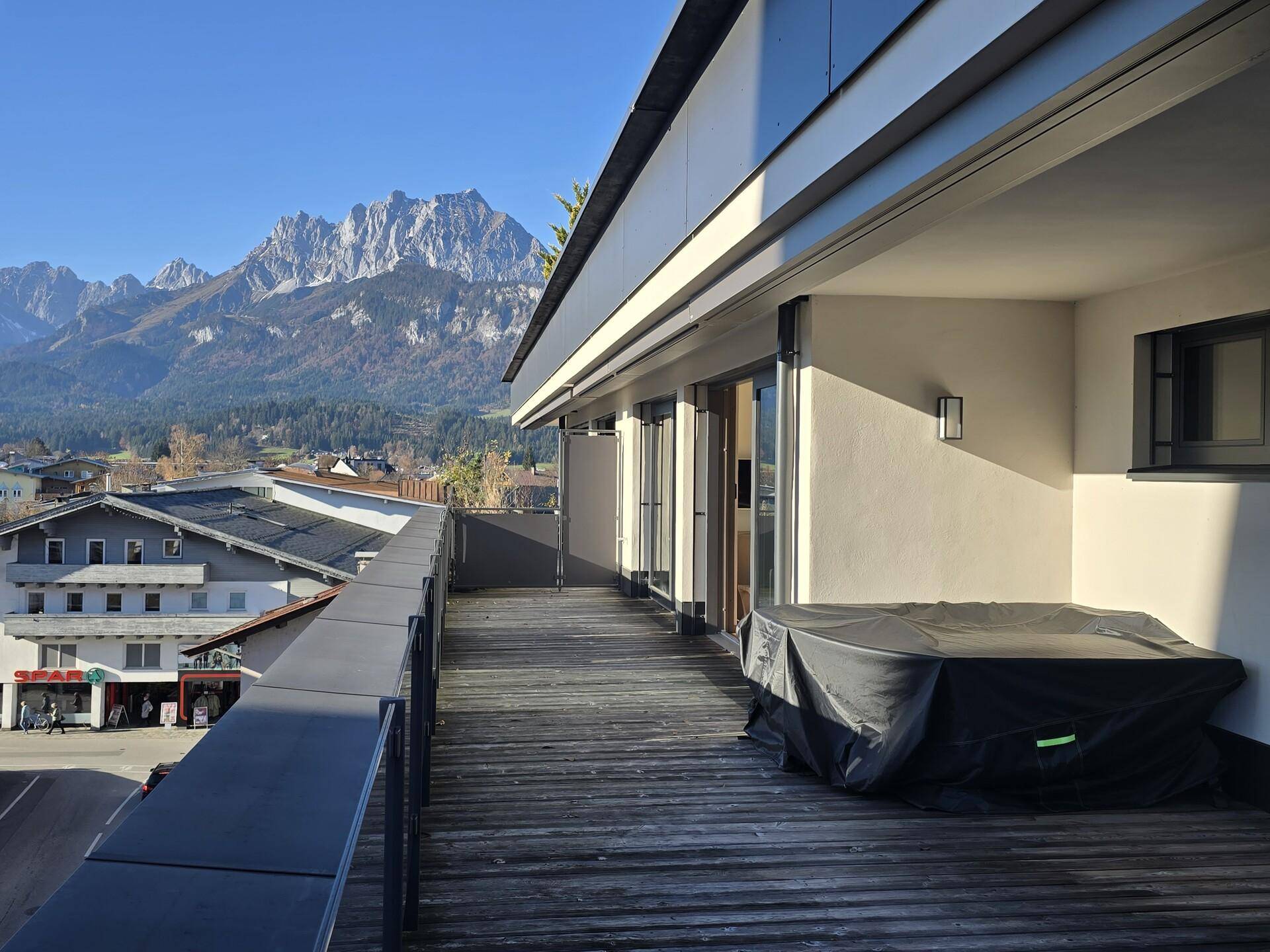 Breite Terrasse mit Holzboden und atemberaubendem Blick auf die schneebedeckten Berge.