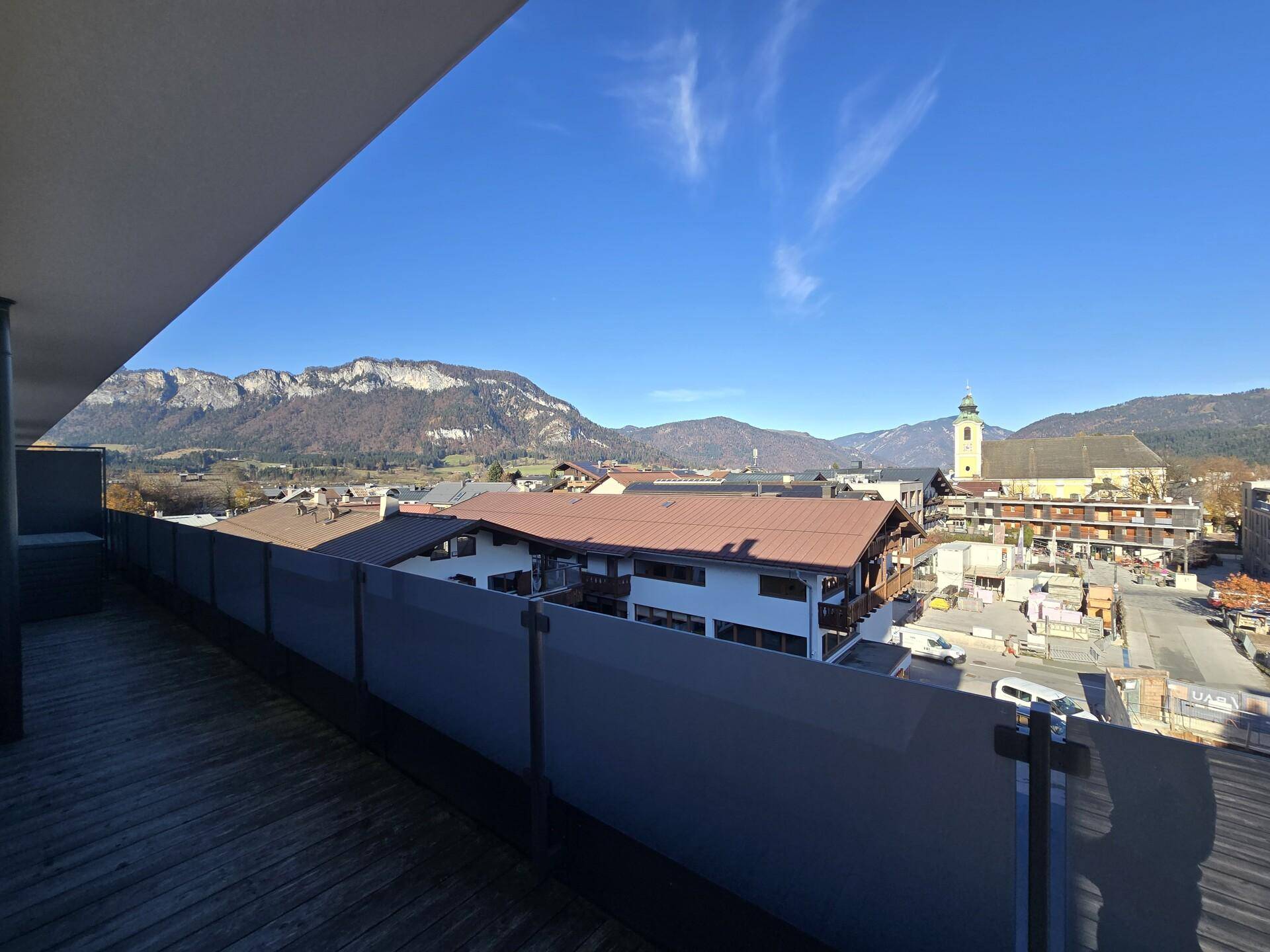Geräumige Terrasse mit Holzboden und Panoramablick auf die Stadt und die majestätischen Berge.