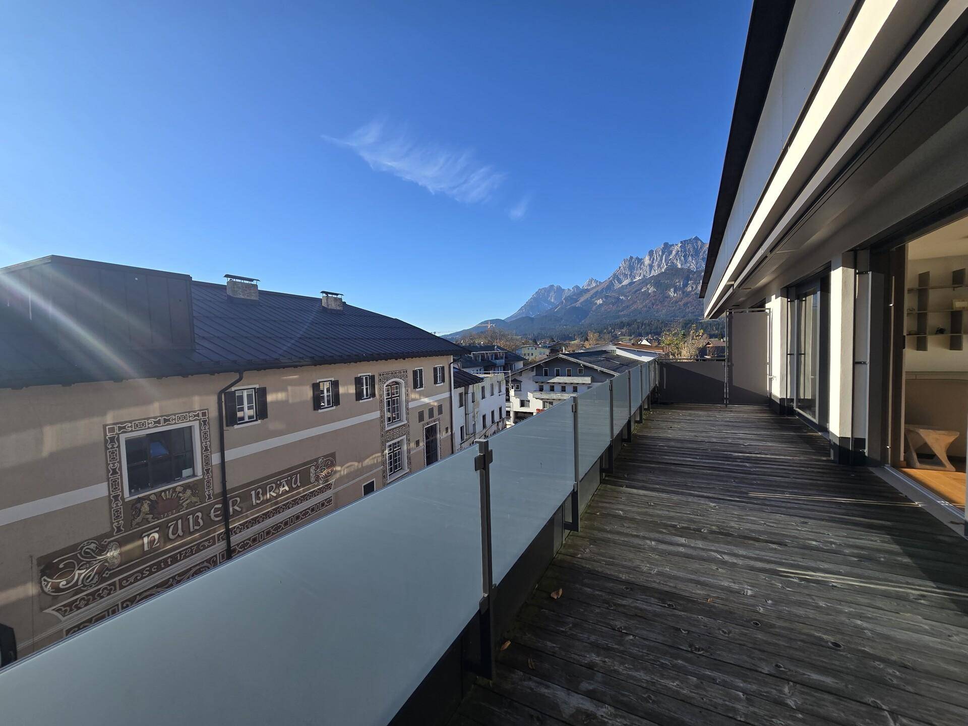 Breite Terrasse mit Holzboden und atemberaubendem Blick auf die schneebedeckten Berge.