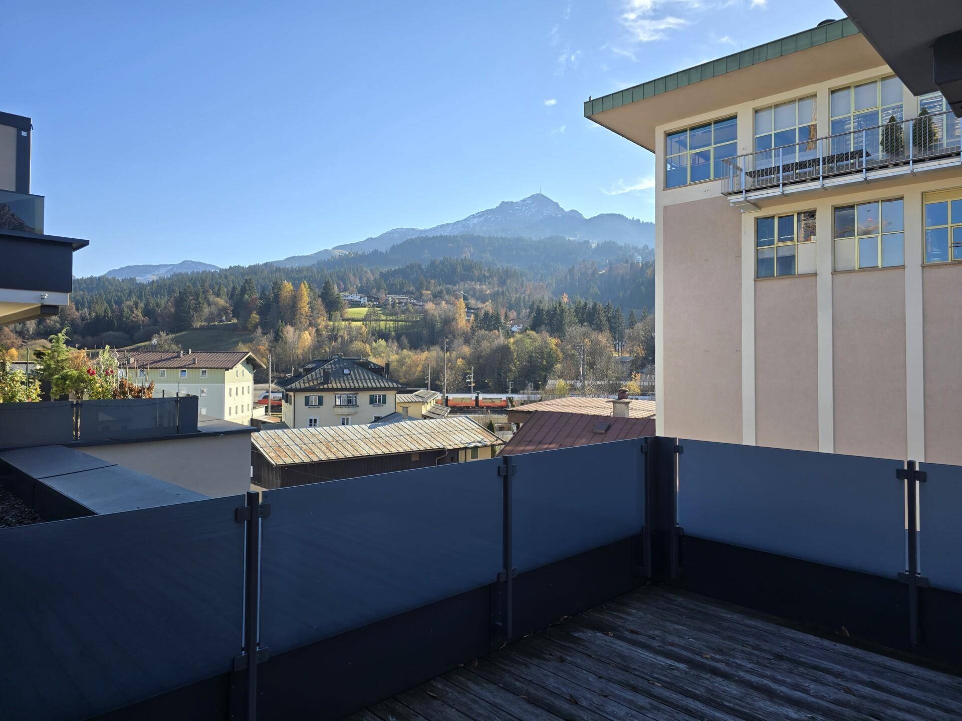 Terrasse mit Holzboden und Glasgeländer bietet einen weiten Blick auf die umliegende Berglandschaft.