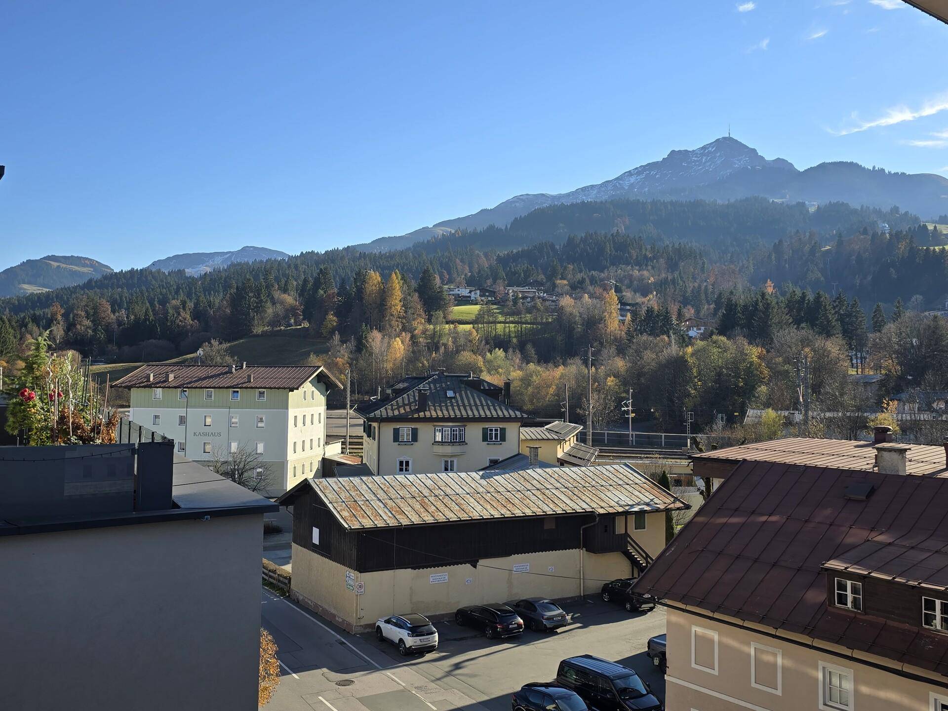 Weitläufiger Blick von der Terrasse auf die umliegende Stadt, grüne Hügel und ferne Berge.
