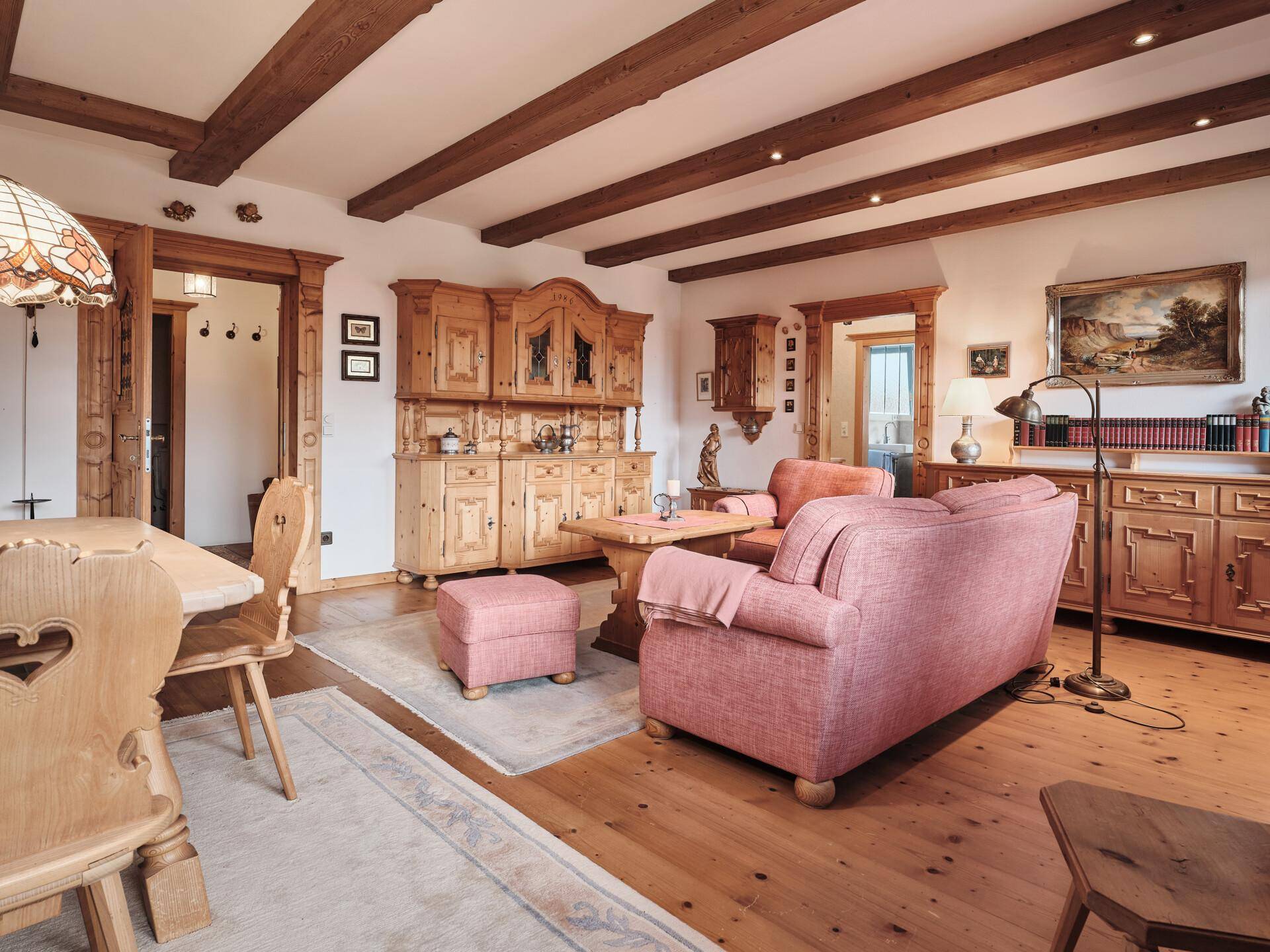 Heller Wohnbereich mit bequemen Sofas, Holzboden und traditionellen Holzmöbeln im alpinen Stil.