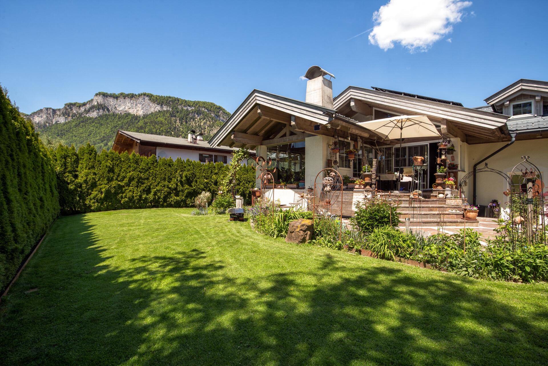 Weitläufiger Rasenbereich mit Blick auf die Berge und die Terrasse des Hauses.