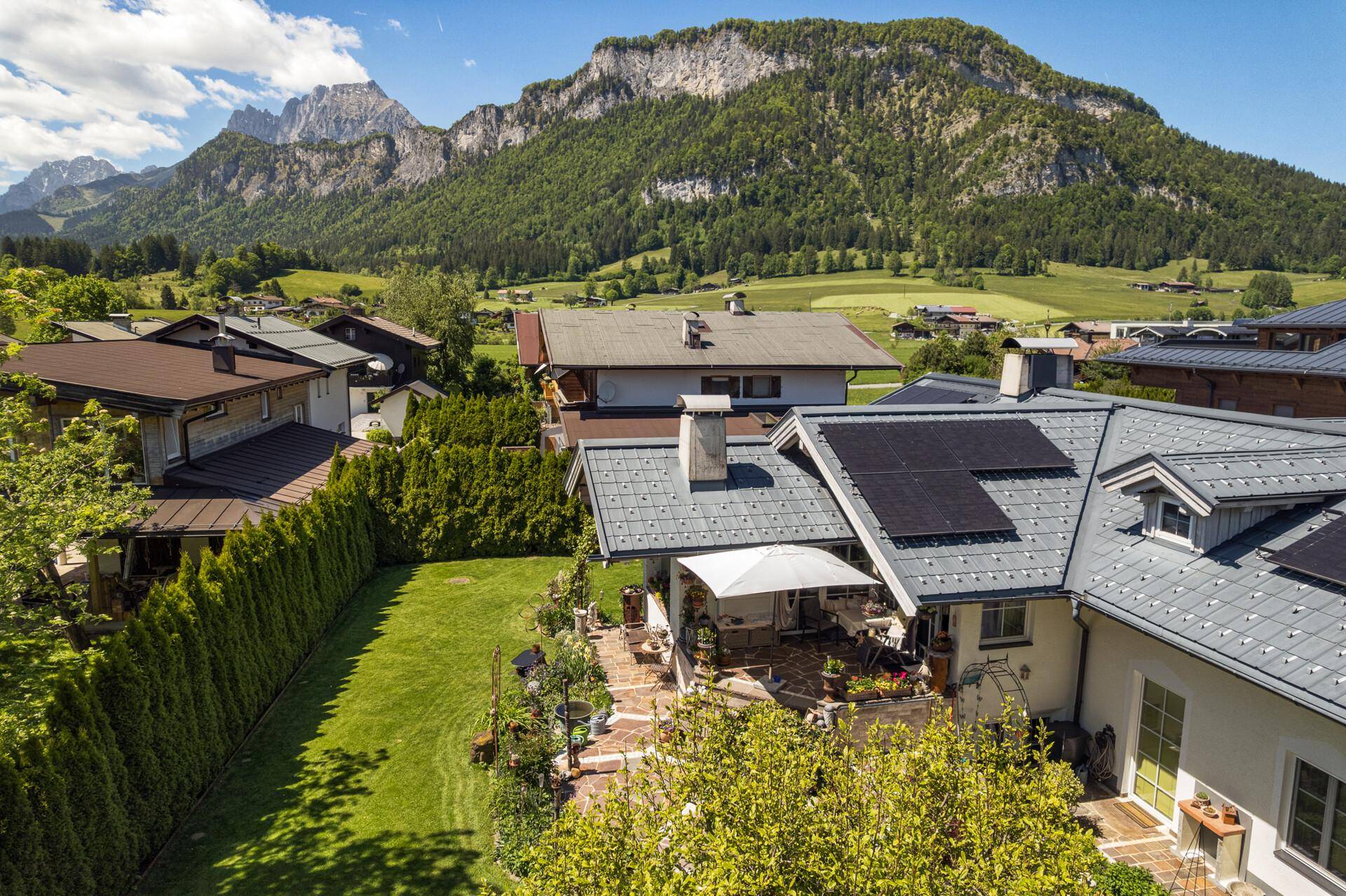 Luftaufnahme des Hauses mit Garten, Terrasse und Blick auf die umliegende Berglandschaft.