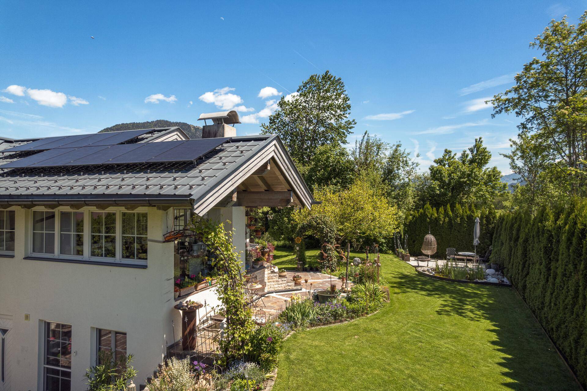 Seitenansicht des Hauses mit Photovoltaikanlage auf dem Dach und weitläufigem Garten.