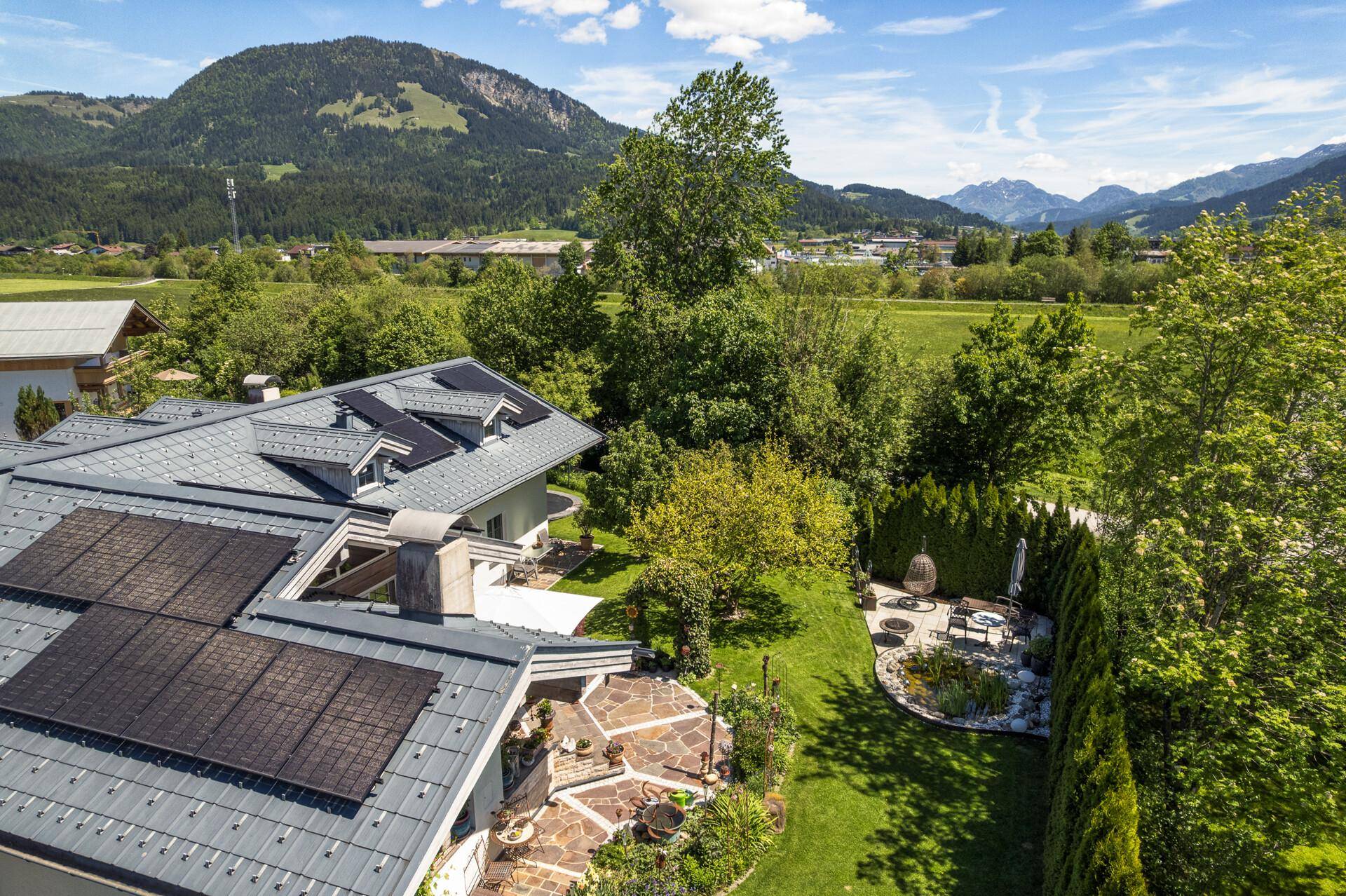Luftaufnahme des Anwesens mit Photovoltaikanlage, Garten und umliegender grüner Landschaft.