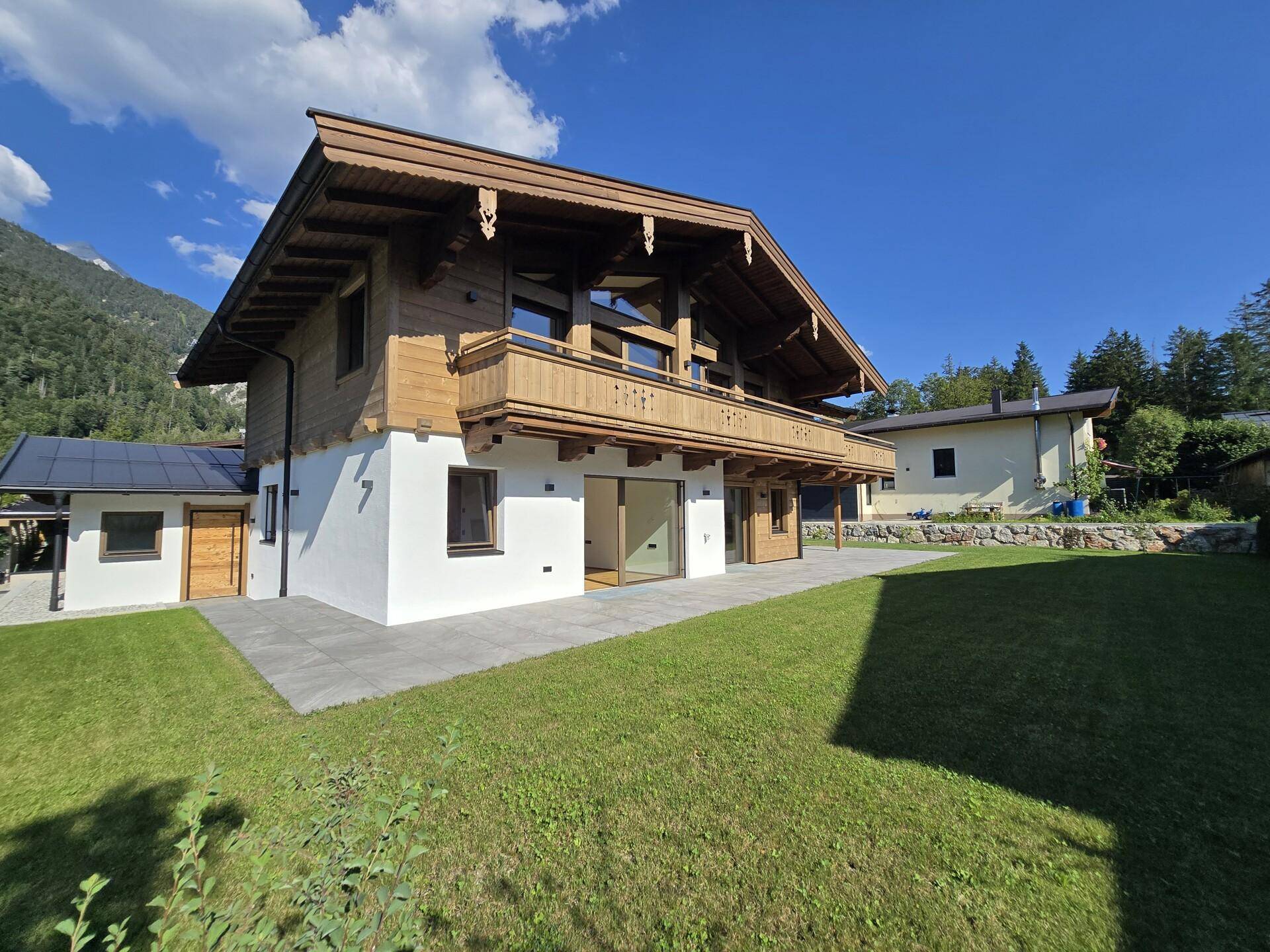 Neubau-Chalet mit großem Garten und Terrasse, umgeben von grüner Natur und Bergen.