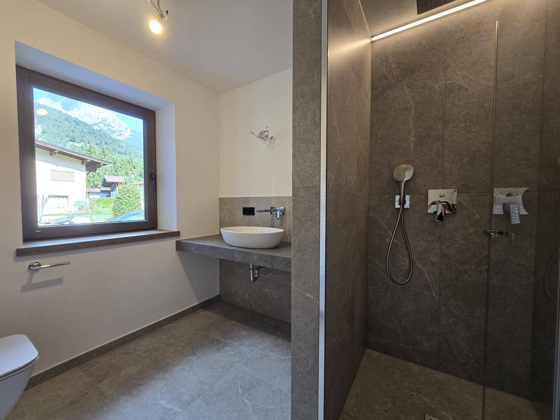 Modernes Badezimmer mit ebenerdiger Dusche, Einzelwaschbecken und Fenster mit Bergblick.