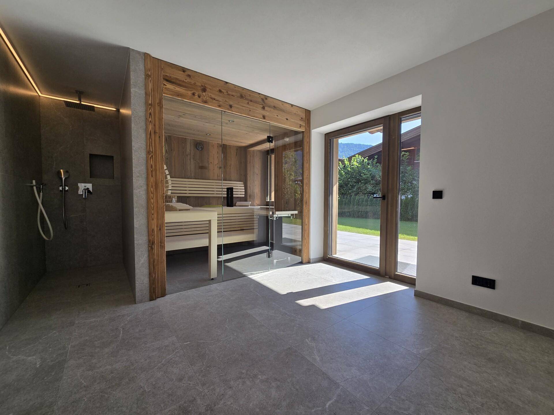 Exklusiver Wellnessbereich mit Sauna, moderner Dusche und Zugang zum Garten.