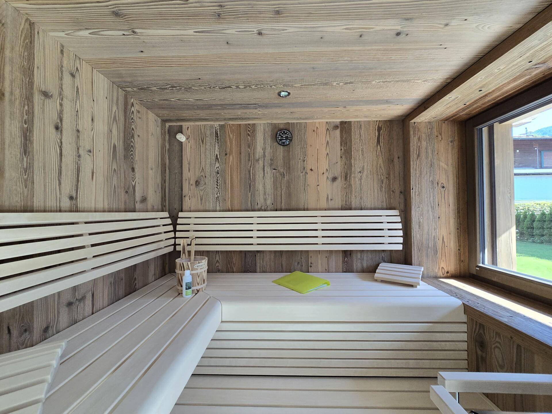 Geräumige Holzsauna mit bequemen Bänken und einem Fenster für natürliche Belüftung.