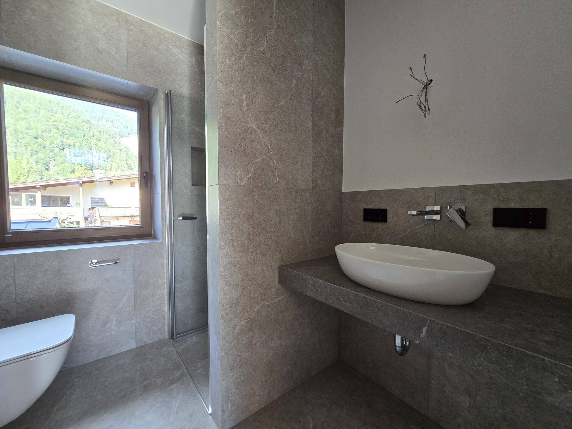 Modernes Badezimmer mit Einzelwaschbecken, Wand-WC und Duschbereich.