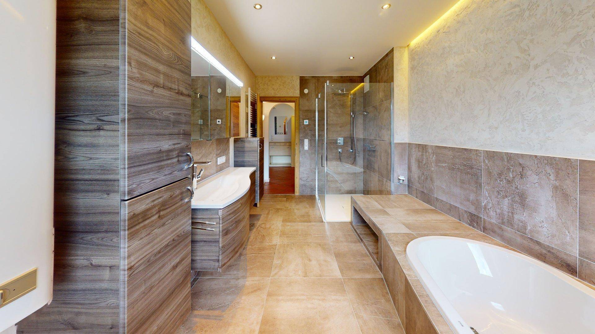 Luxuriöses Badezimmer mit großformatigen Fliesen, begehbarer Dusche und integrierter Badewanne.
