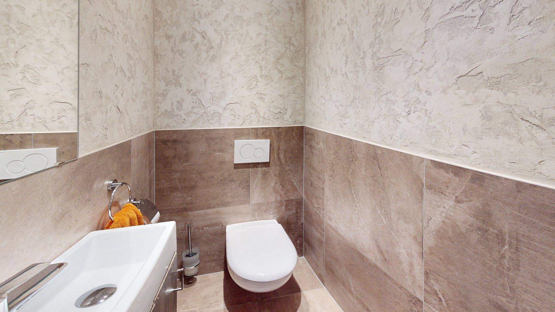 Modernes Gäste-WC mit wandhängender Toilette und stilvollen Fliesen an den Wänden.