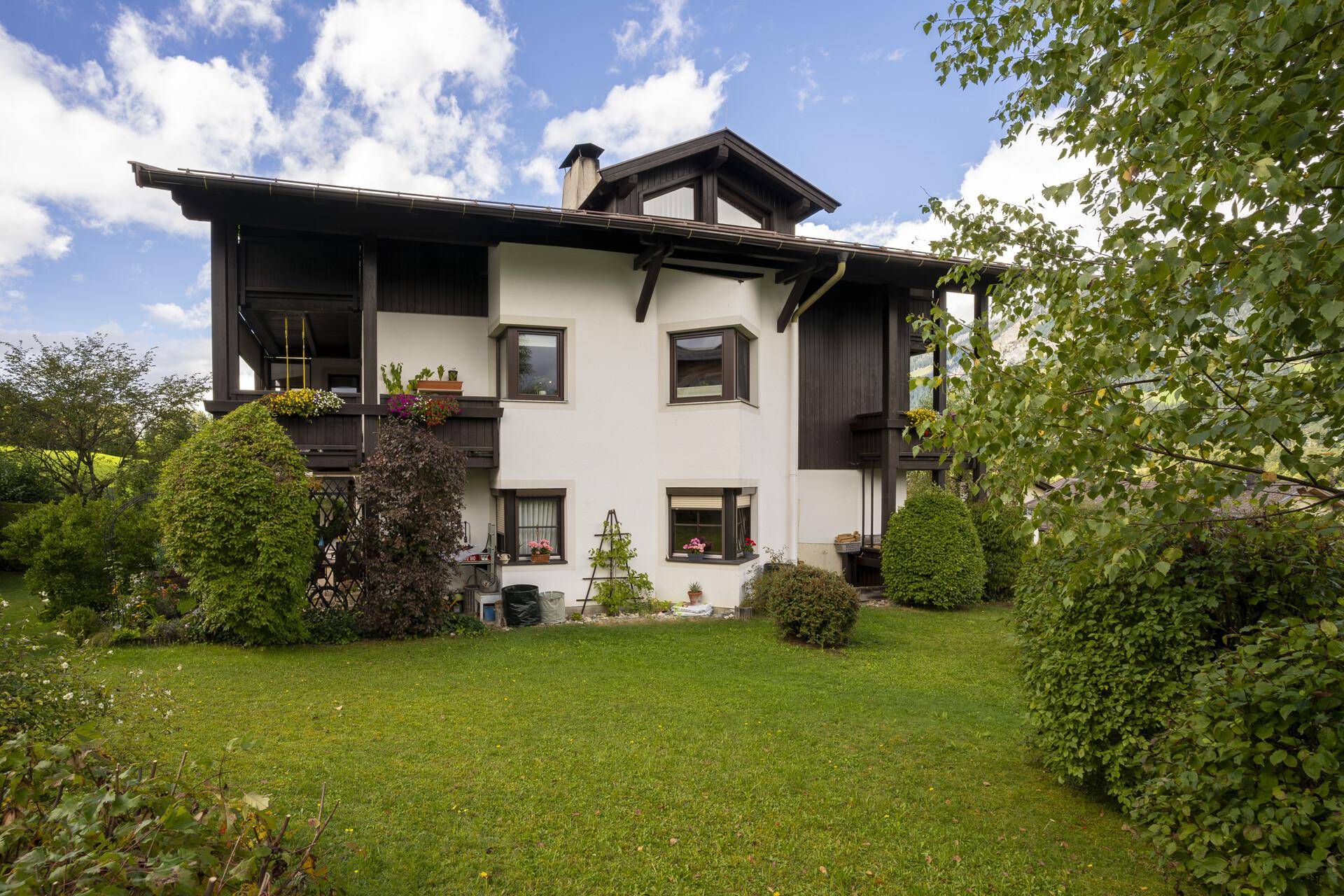 Traditionelles Haus mit gepflegtem Garten, Rasenflächen und üppiger Bepflanzung.