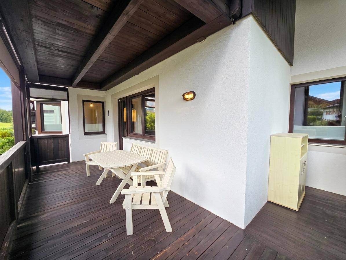 Überdachte Loggia mit Holzboden und Sitzgelegenheiten, ideal für entspannte Stunden im Freien.