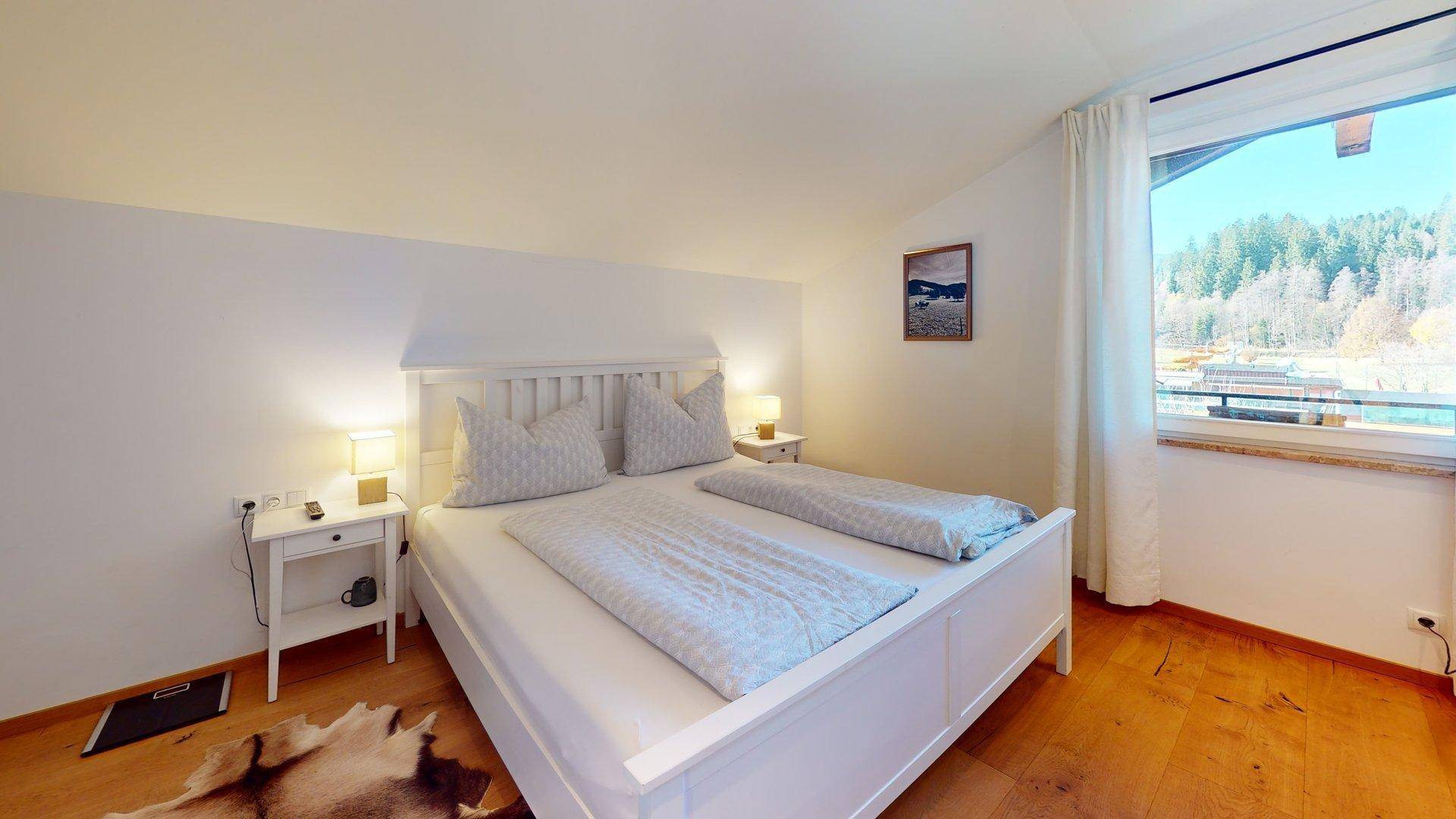 Gemütliches Schlafzimmer mit Doppelbett und Fenster, das einen weiten Blick ins Grüne bietet.