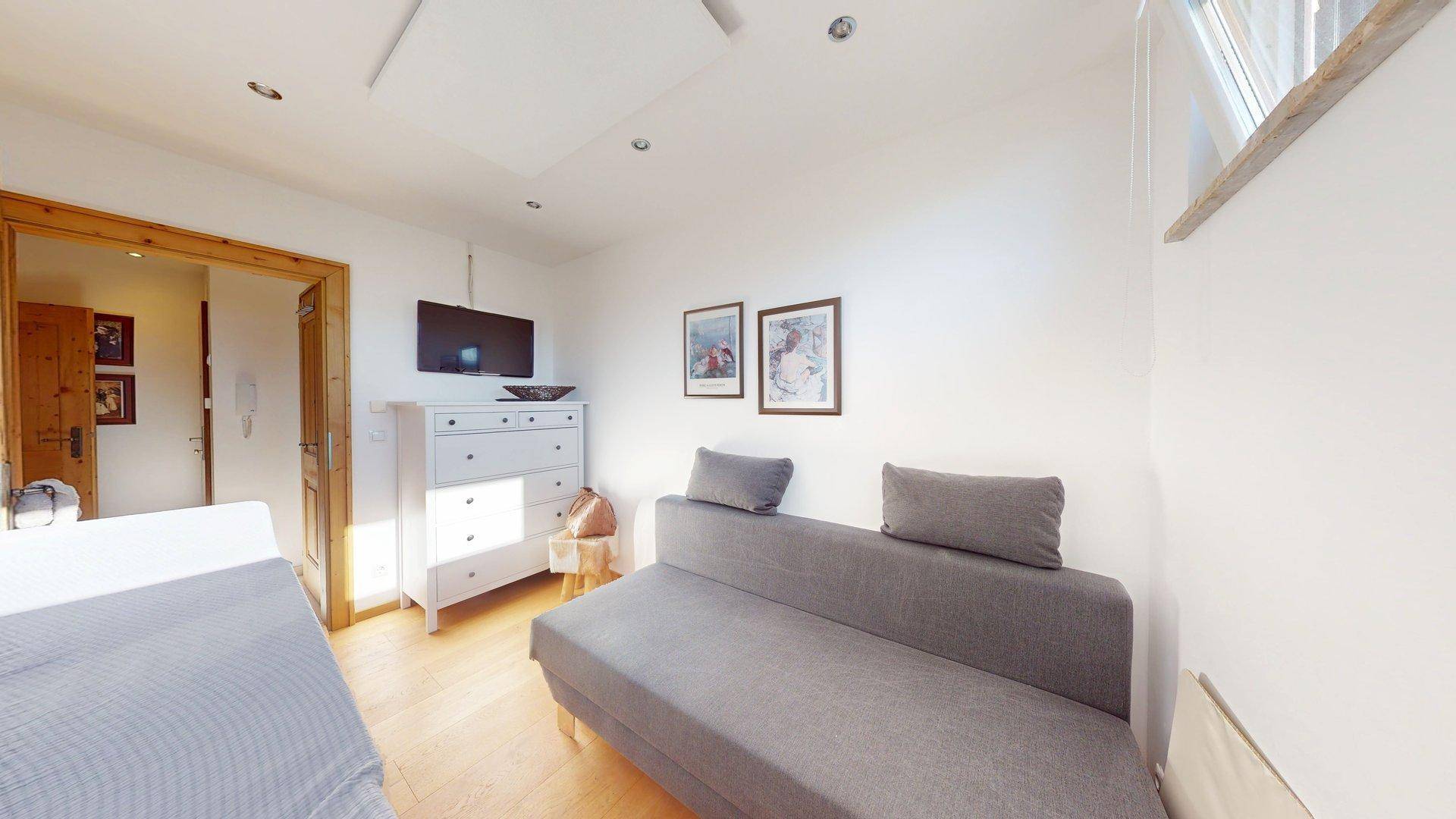 Gemütliches Schlafzimmer mit Schlafsofa, Kommode und Holzboden, ideal als Gästezimmer.