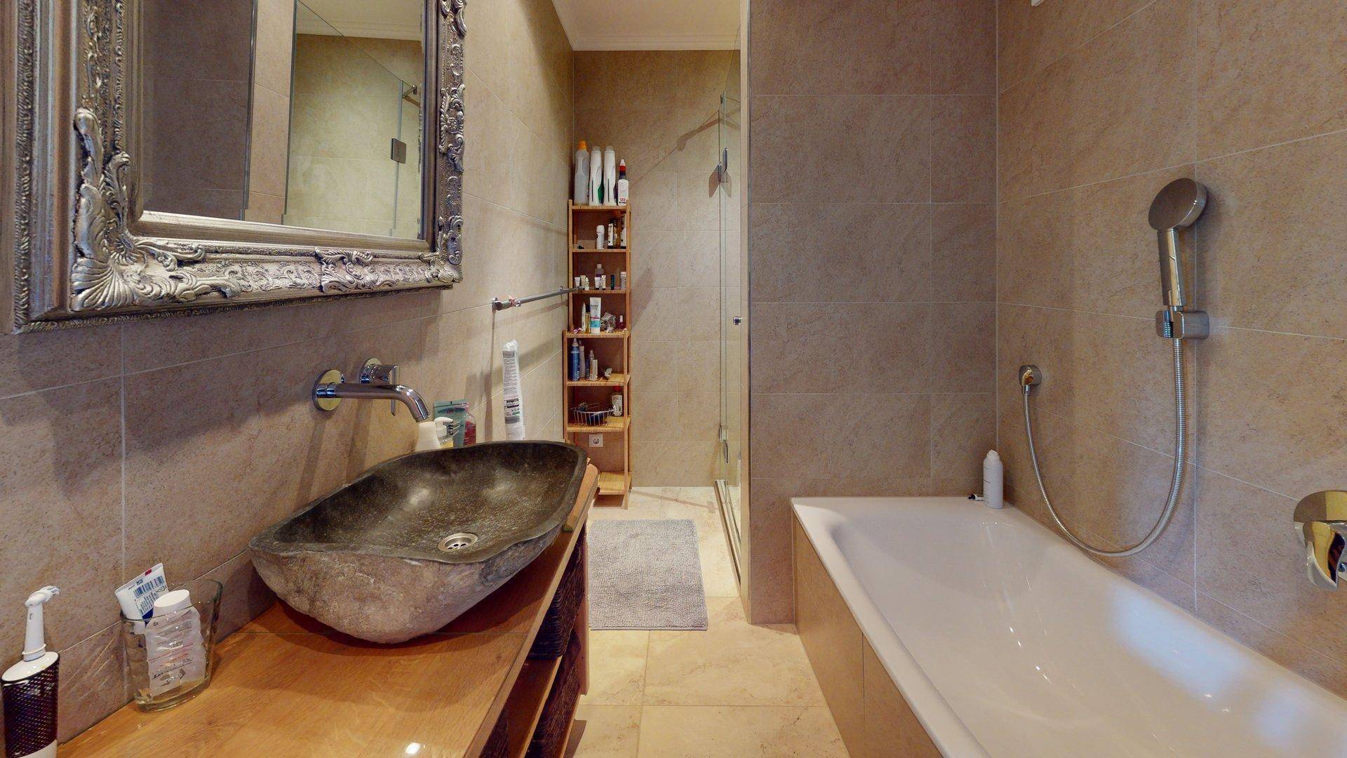 Modernes Badezimmer mit Badewanne, Dusche und einzigartigem Steinwaschbecken.