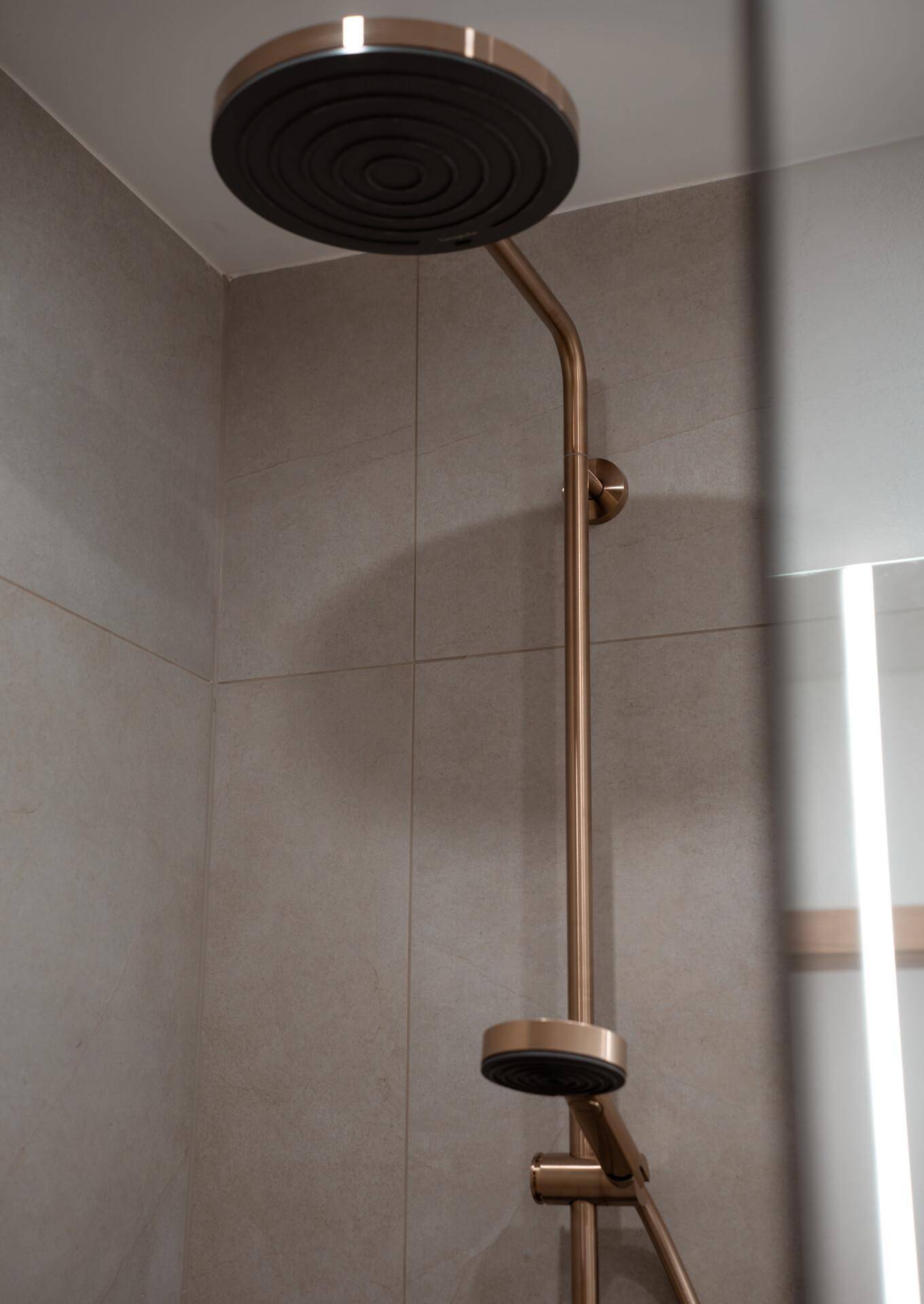 Detailansicht einer modernen Regendusche mit bronzefarbenen Armaturen.