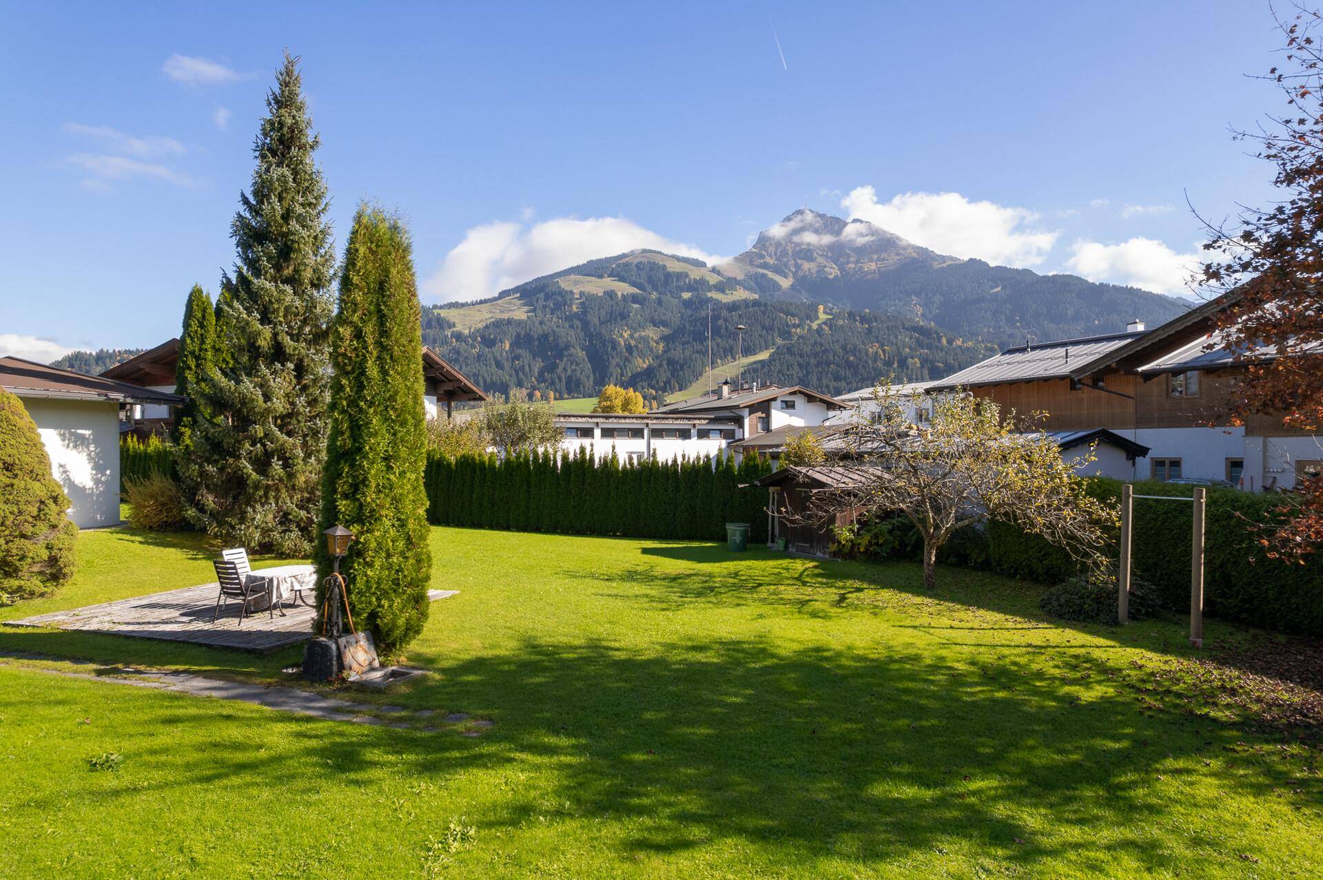 Gepflegter Garten mit Rasenfläche und herrlichem Blick auf die umliegende Berglandschaft unter blauem Himmel.