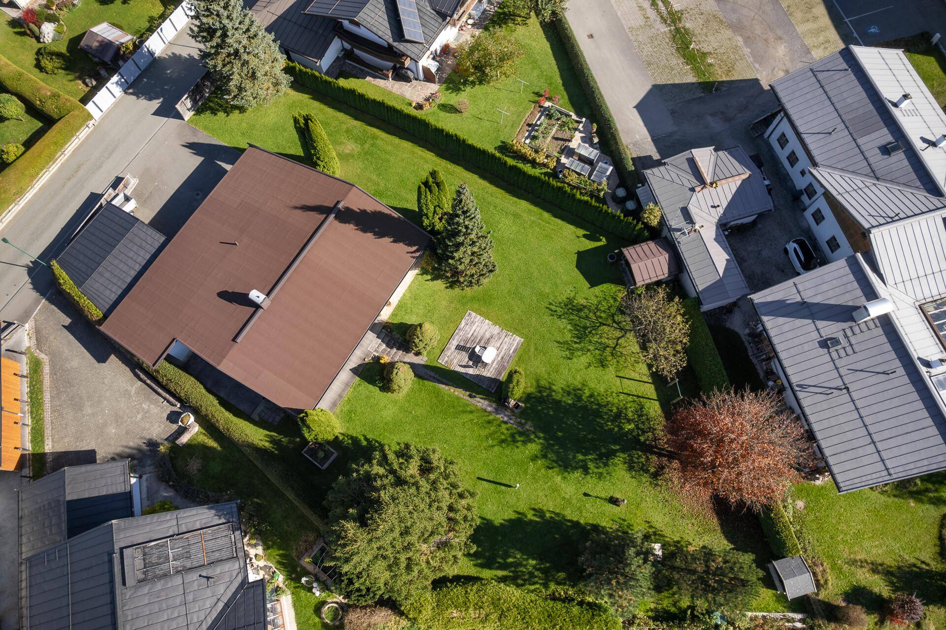 Vogelperspektive des Grundstücks mit Einfamilienhaus, gepflegtem Garten und angrenzenden Gebäuden in ländlicher Umgebung.