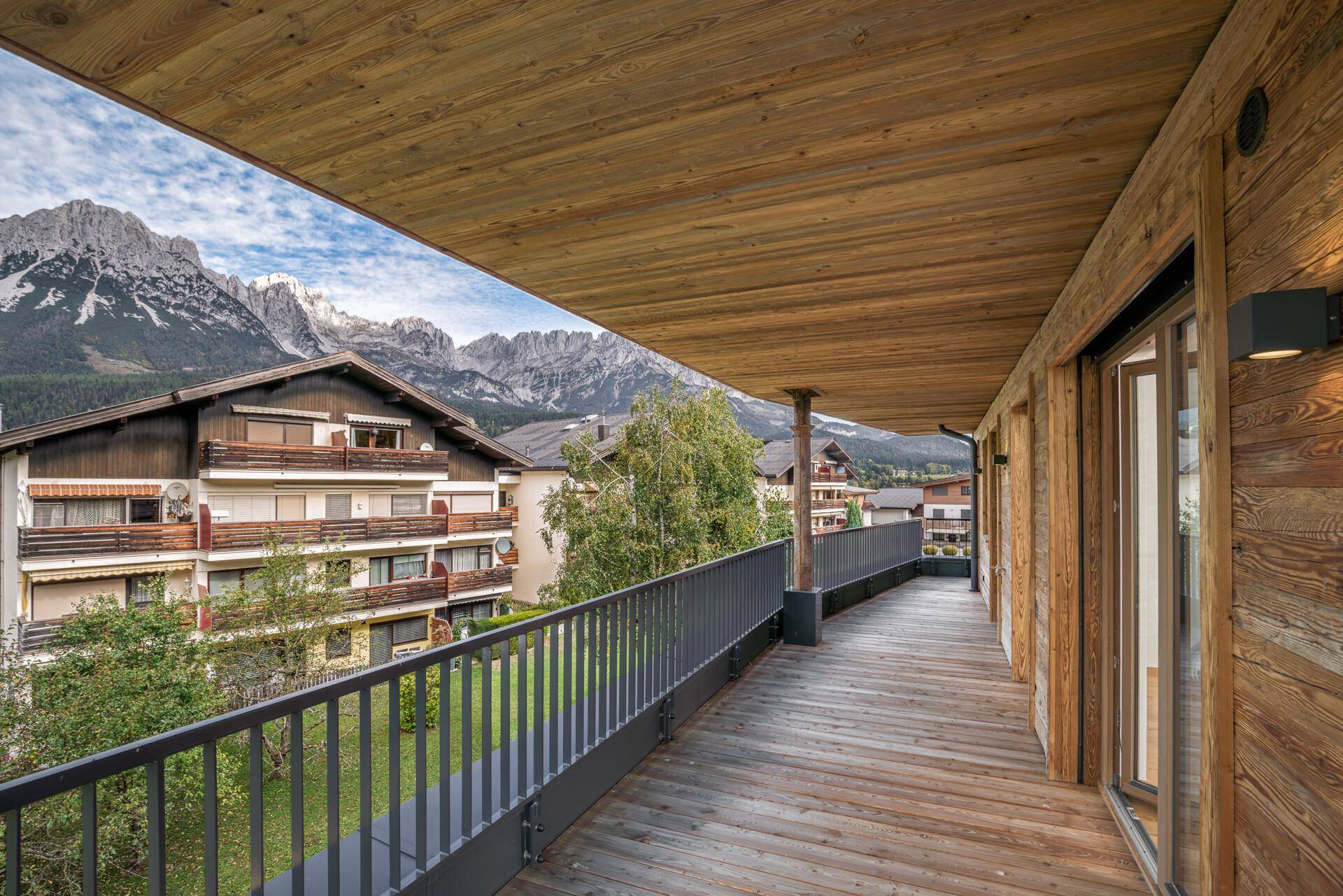 Langer, überdachter Holzbalkon mit atemberaubendem Panoramablick auf die umliegende Berglandschaft.