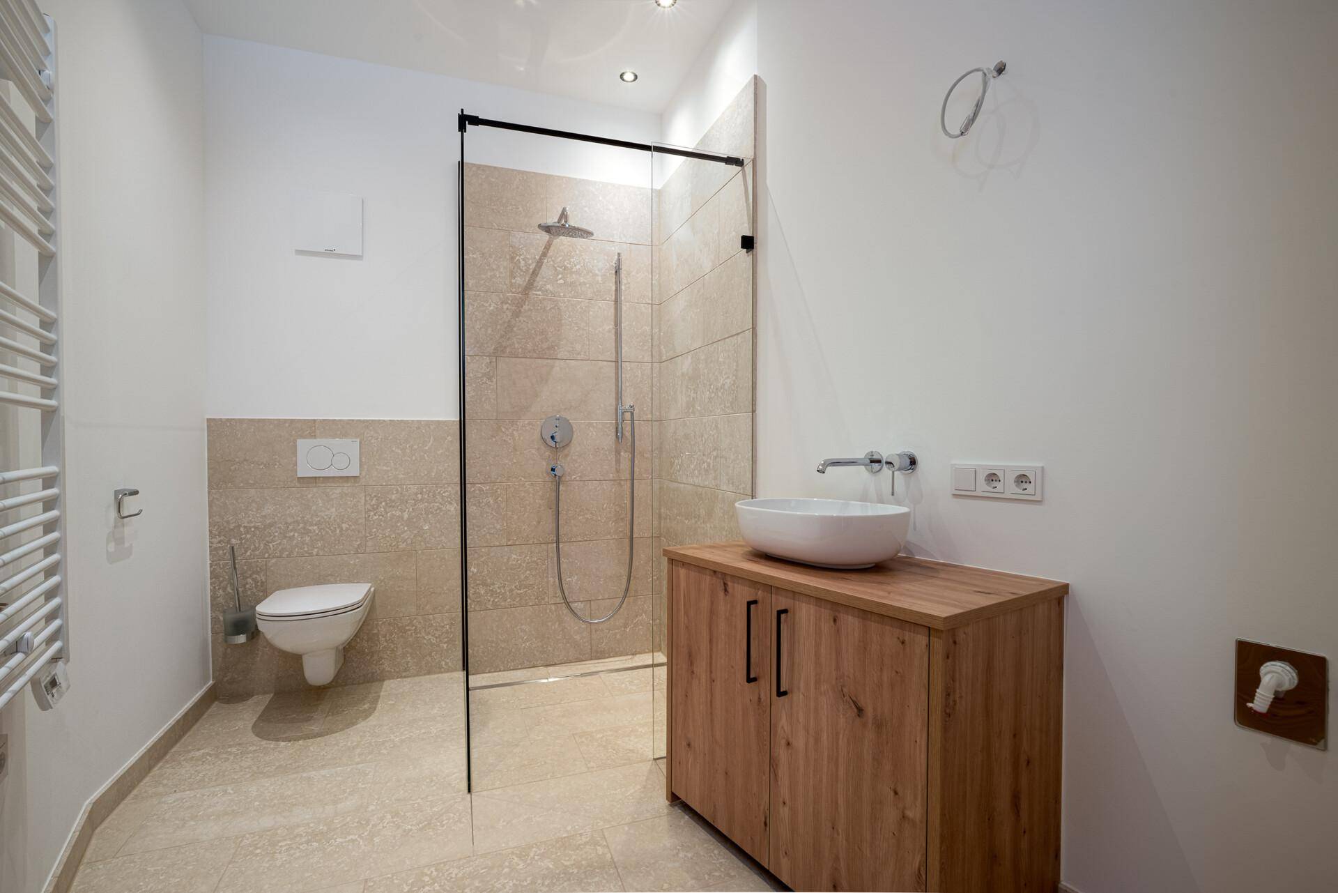 Modernes Badezimmer mit begehbarer Dusche, wandhängendem WC und Einzelwaschbecken.