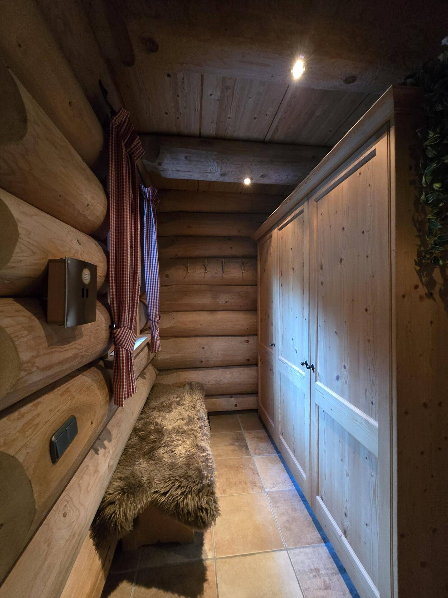 Eingangsbereich mit Holzwänden, Einbauschrank und gemütlicher Sitzbank mit Fellauflage.