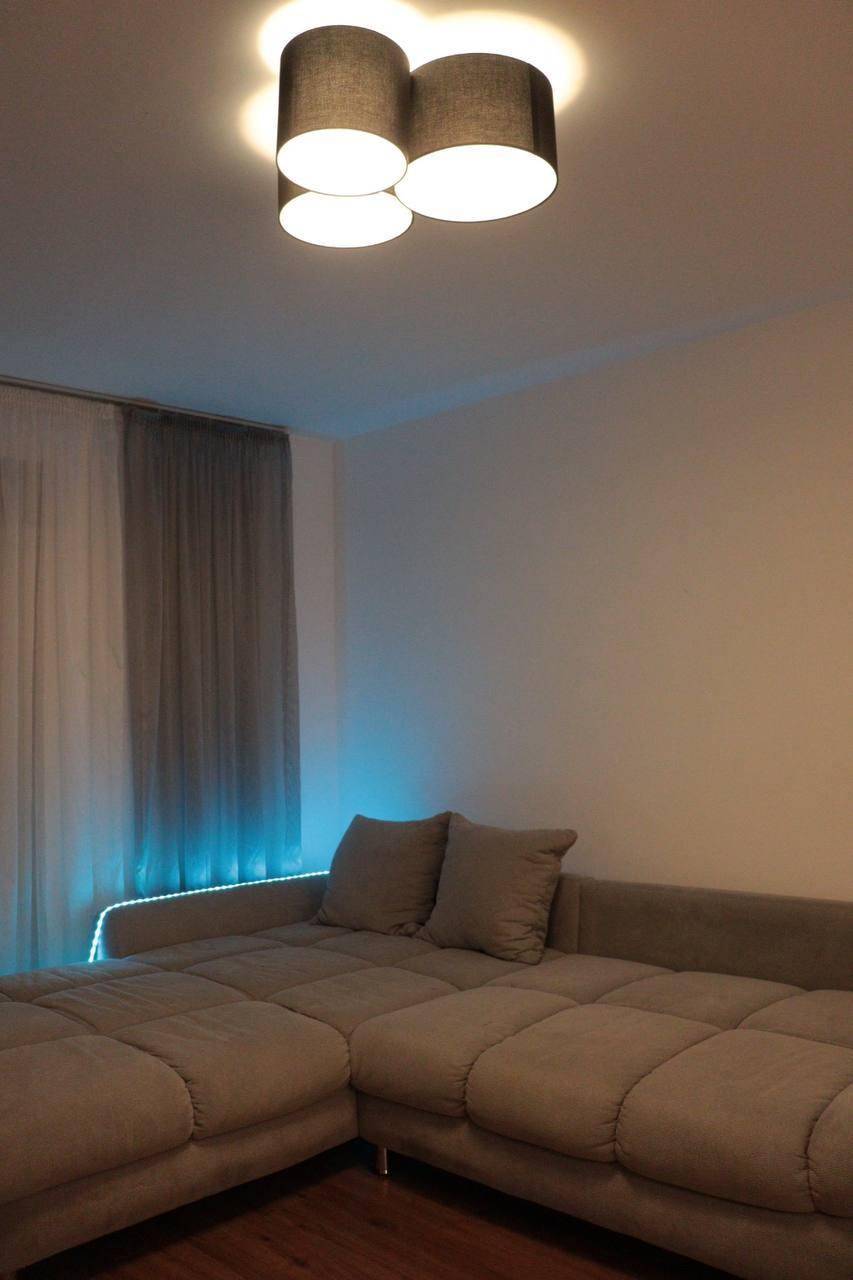 Geräumiges Wohnzimmer mit großem Ecksofa und indirekter blauer Beleuchtung für eine entspannte Atmosphäre.
