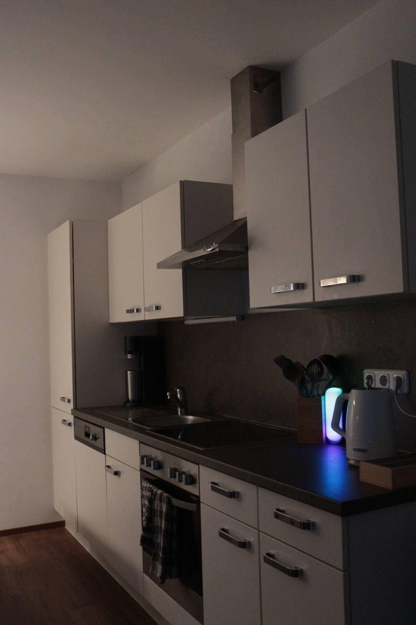 Moderne Küche mit weißen Schränken, dunkler Arbeitsplatte und integrierten Küchengeräten.