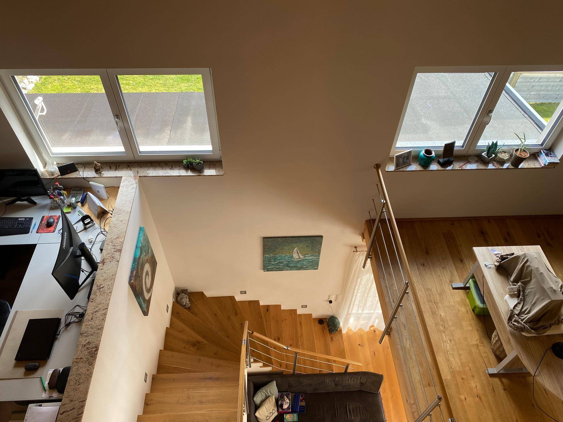 Blick von oben auf die offene Treppe und den darunter liegenden Wohnbereich.