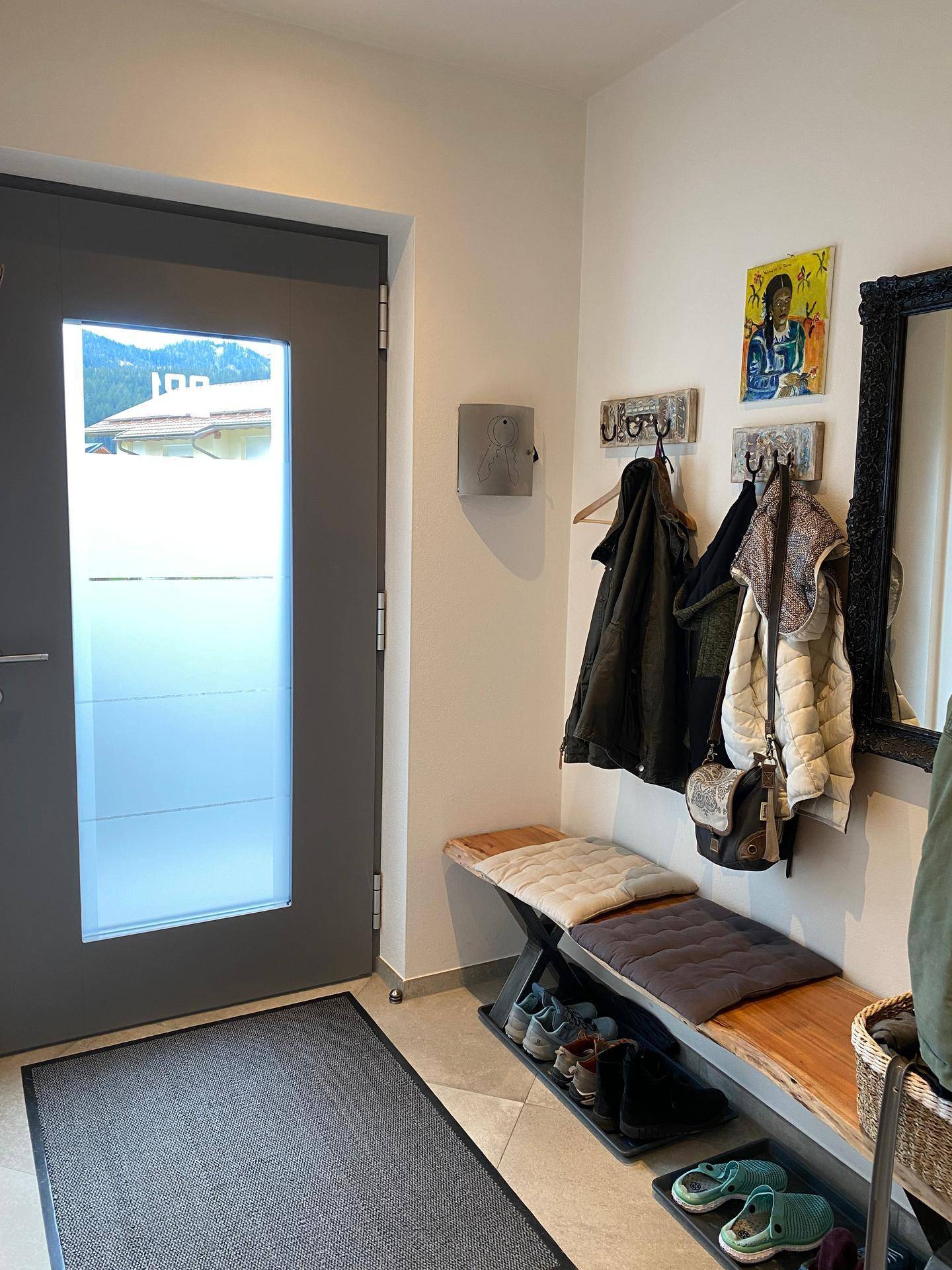 Heller Eingangsbereich mit Garderobe, Sitzbank und Spiegel, einladend gestaltet.
