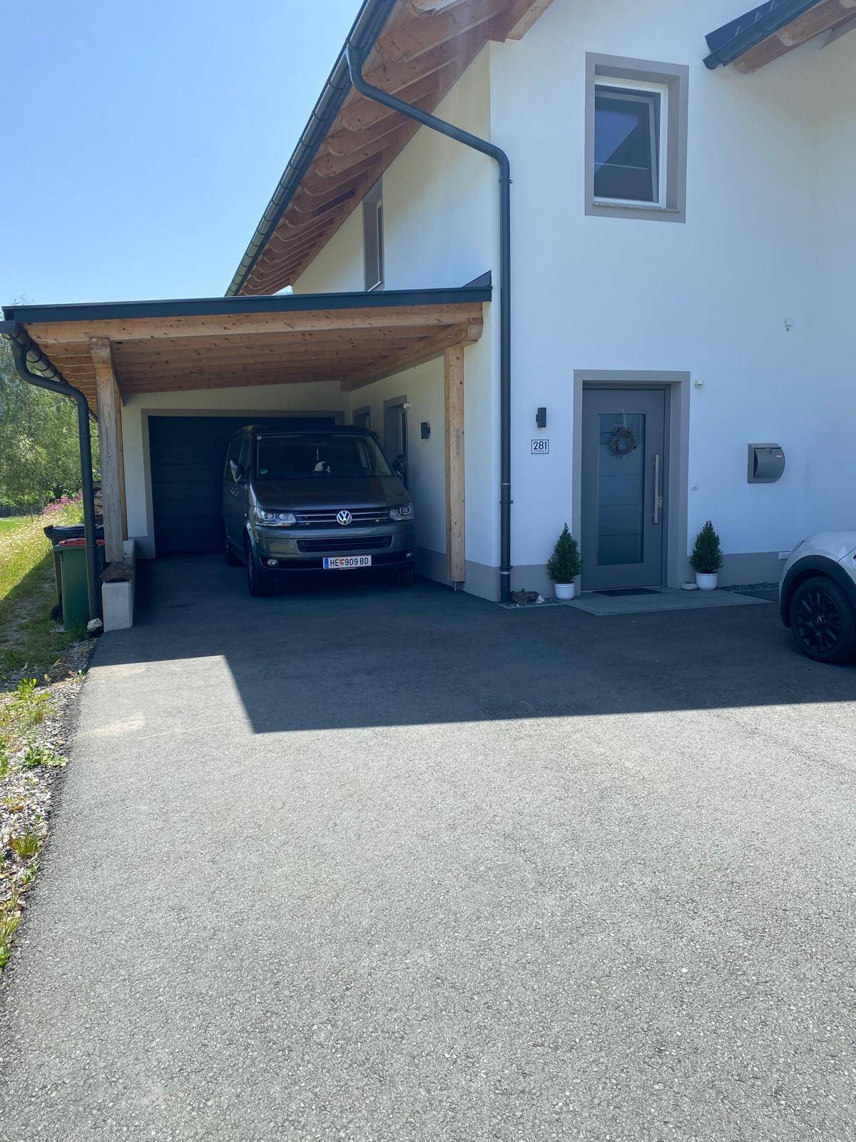 Vorderansicht des Hauses mit Carport, Einfahrt und gepflegtem Eingangsbereich.