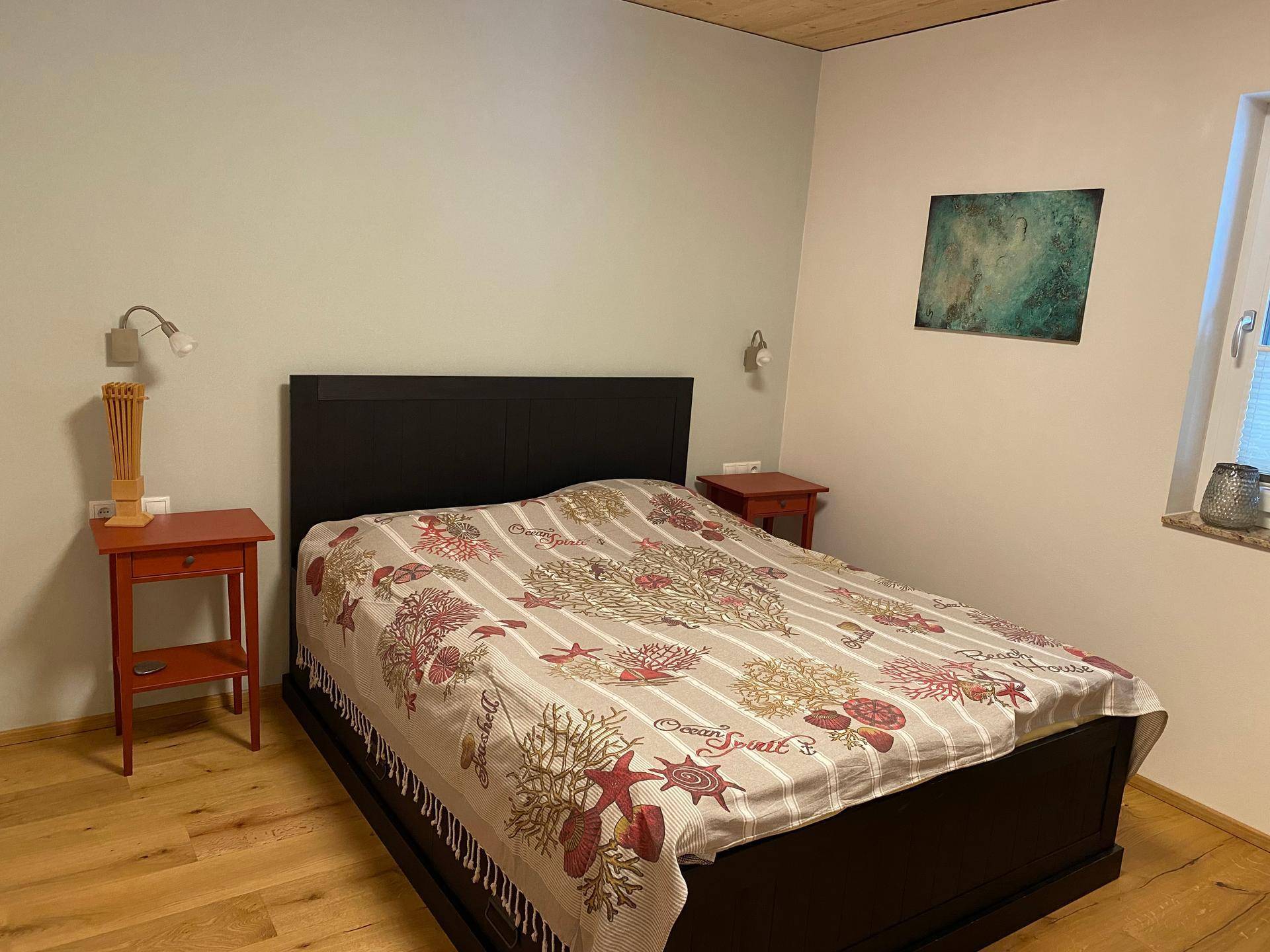 Gemütliches Schlafzimmer mit Doppelbett, Holzboden und Nachttischen in warmen Farbtönen.