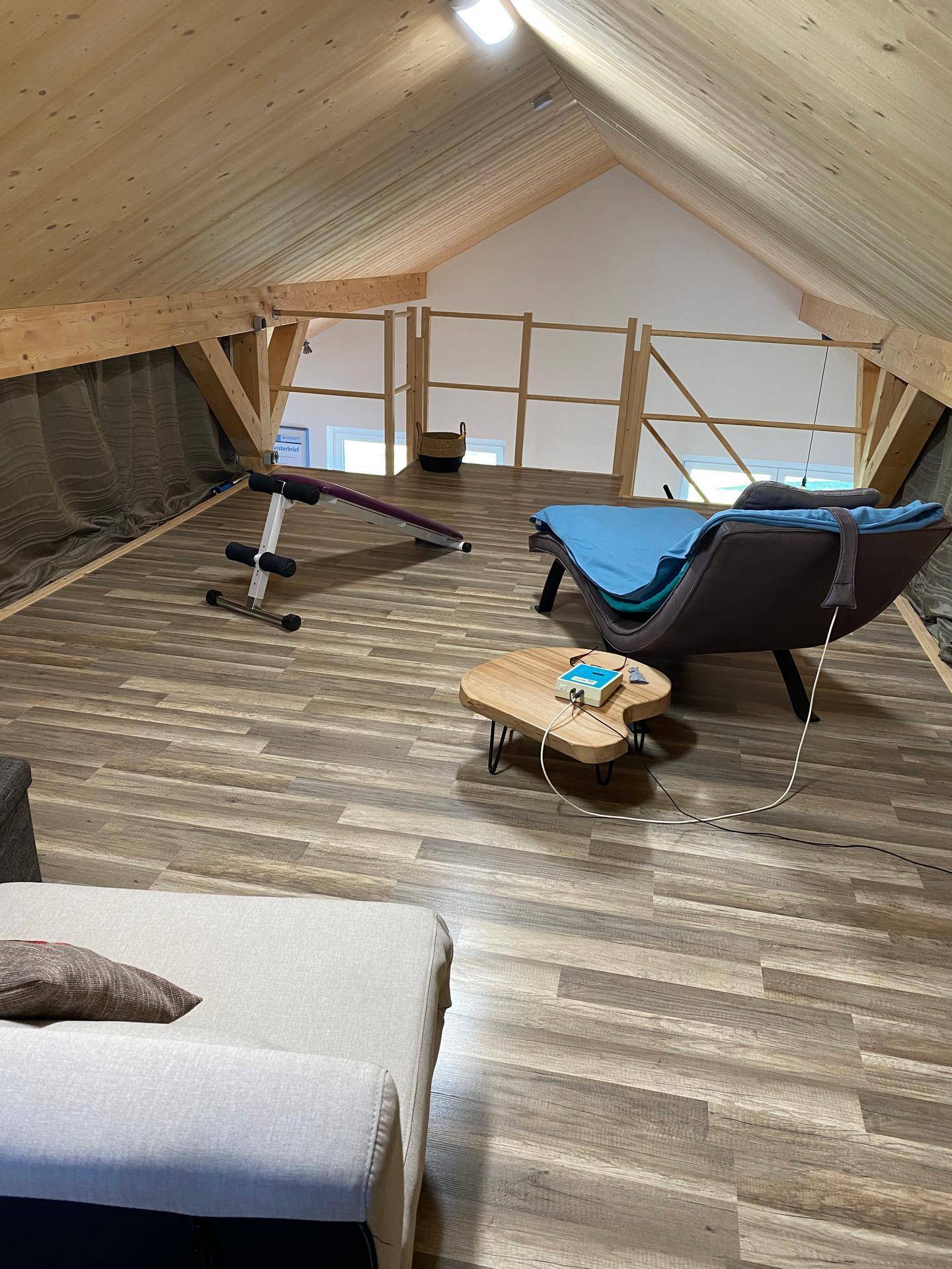 Ausgebauter Dachboden als Entspannungs- oder Fitnessbereich mit Holzbalken und Schrägen.