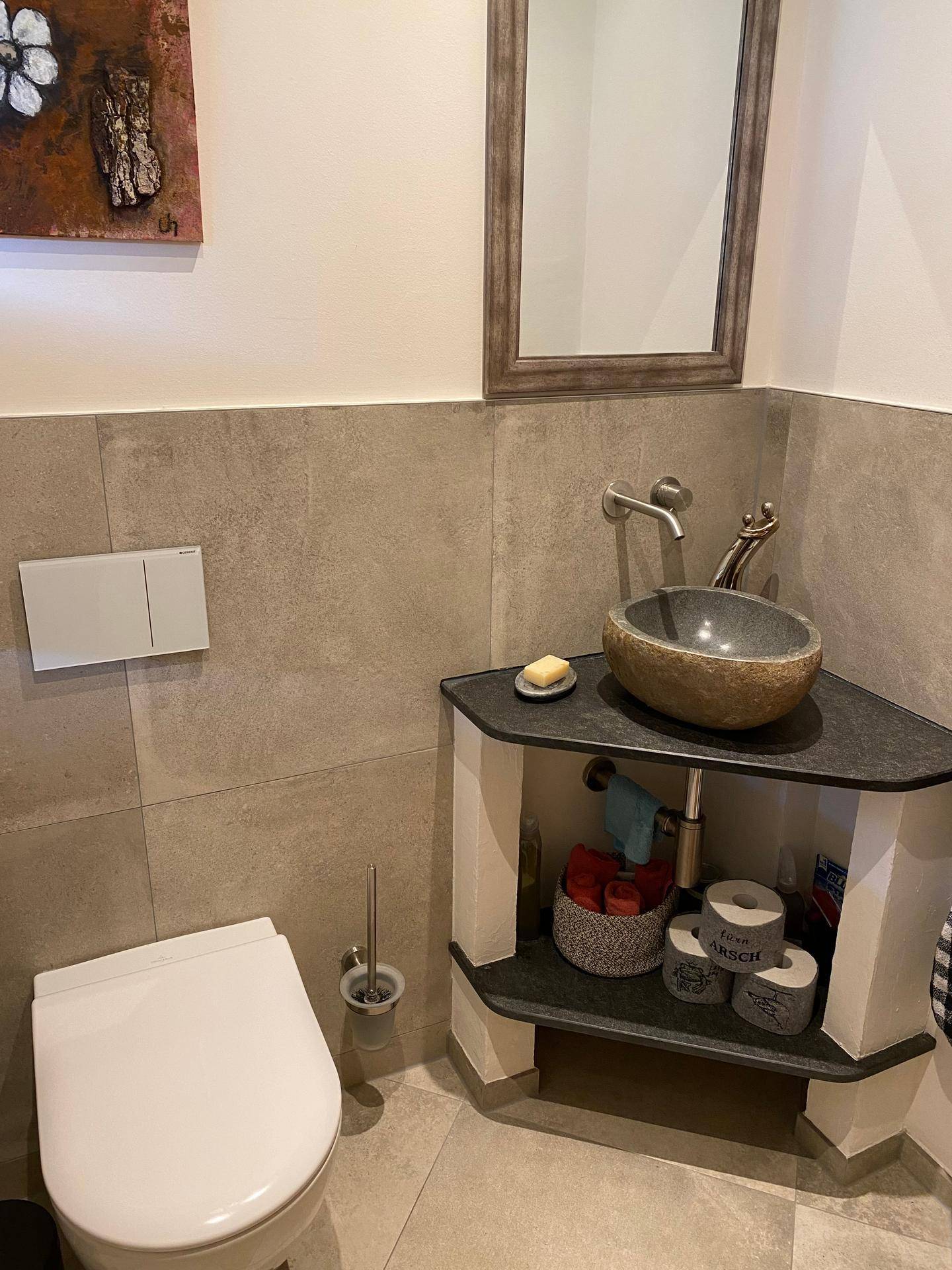 Modernes Gäste-WC mit einzigartigem Steinwaschbecken und Wand-WC.