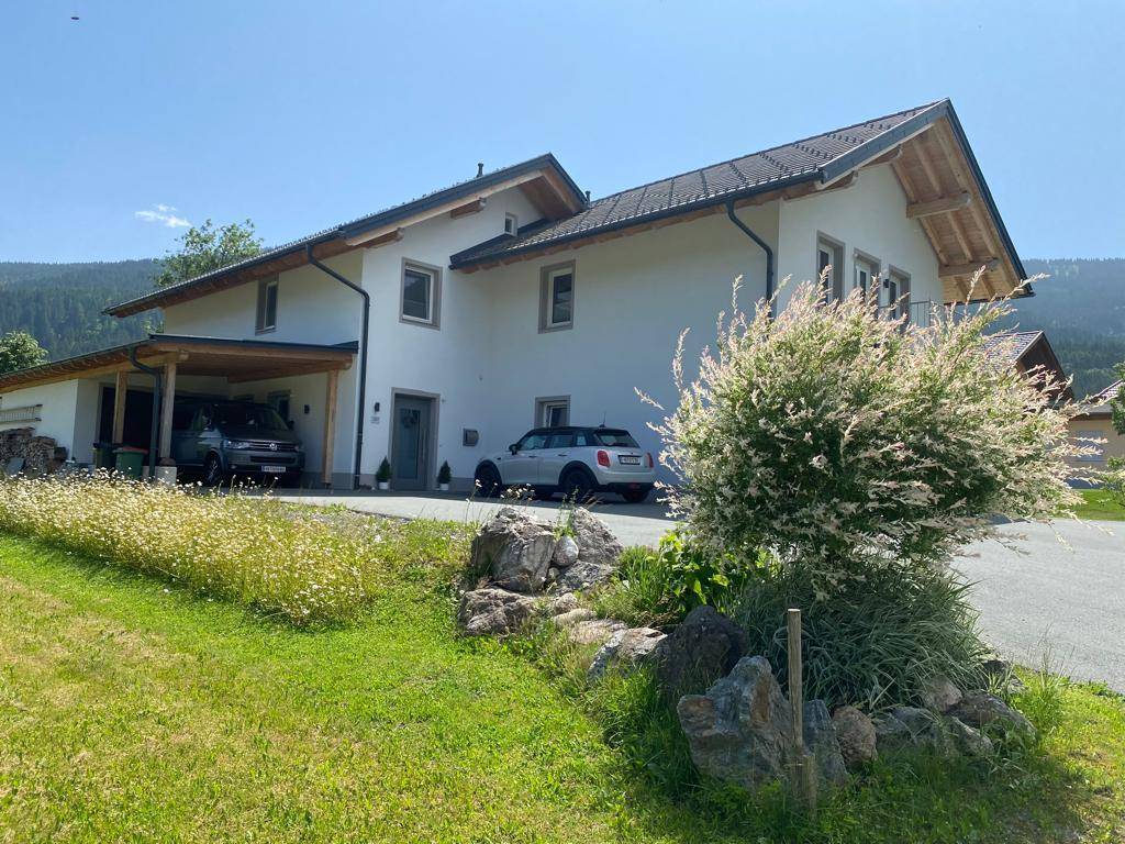 Vorderansicht des modernen Hauses mit Carport, Stellplätzen und gepflegter Zufahrt.