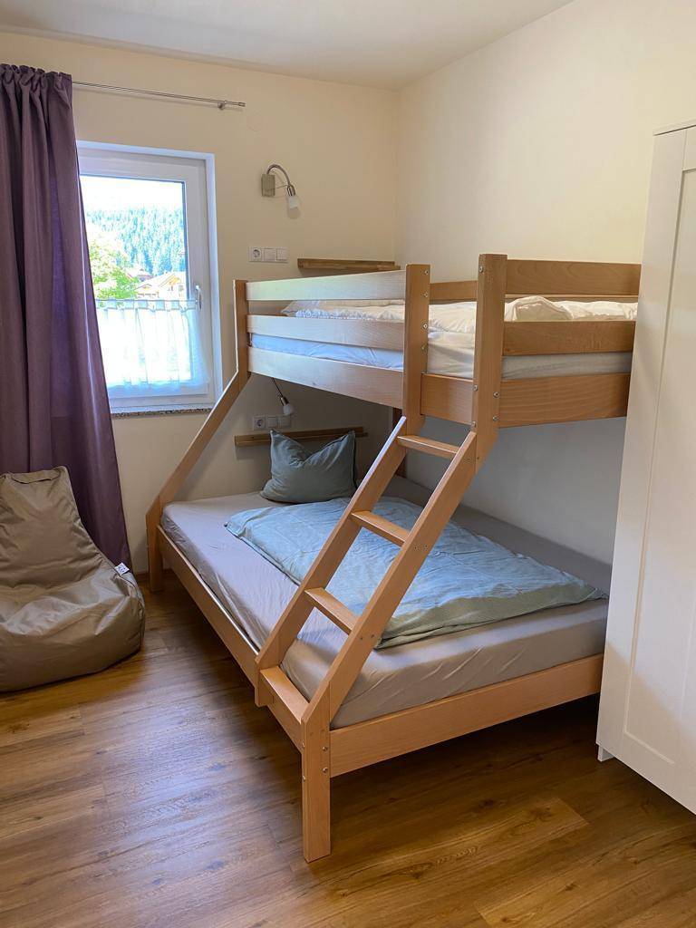 Kinderzimmer mit Etagenbett, Sitzsack und Fenster mit Blick ins Grüne.