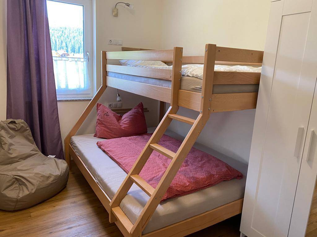 Kinderzimmer mit Etagenbett, Sitzsack und Fenster mit Blick ins Grüne.