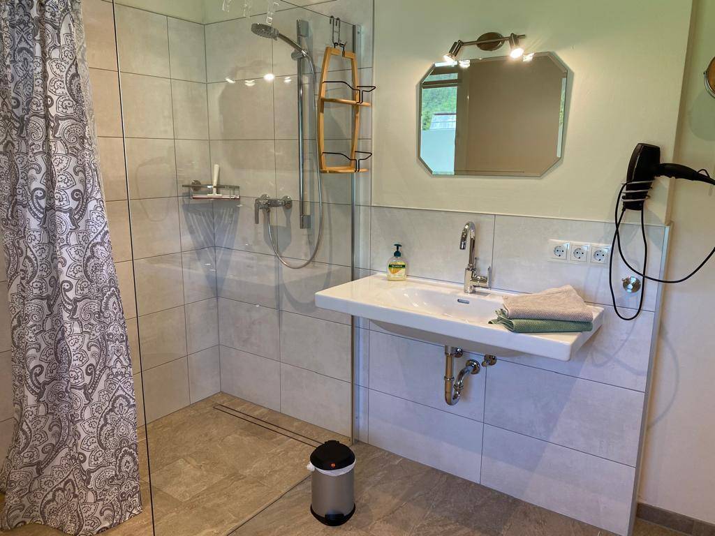 Modernes Badezimmer mit ebenerdiger Dusche, Einzelwaschbecken und großem Spiegel.