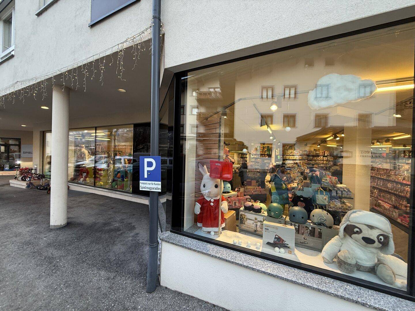 Detailansicht eines Schaufensters mit ausgestellten Spielwaren und einem Parkschild.