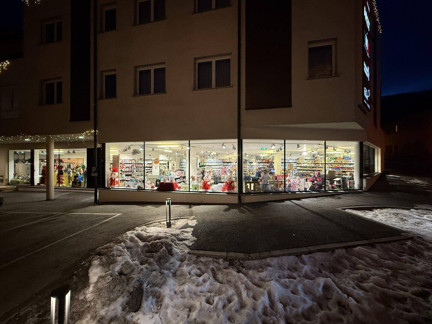Nahaufnahme der beleuchteten Schaufensterfront des Geschäfts bei Nacht mit Schnee.