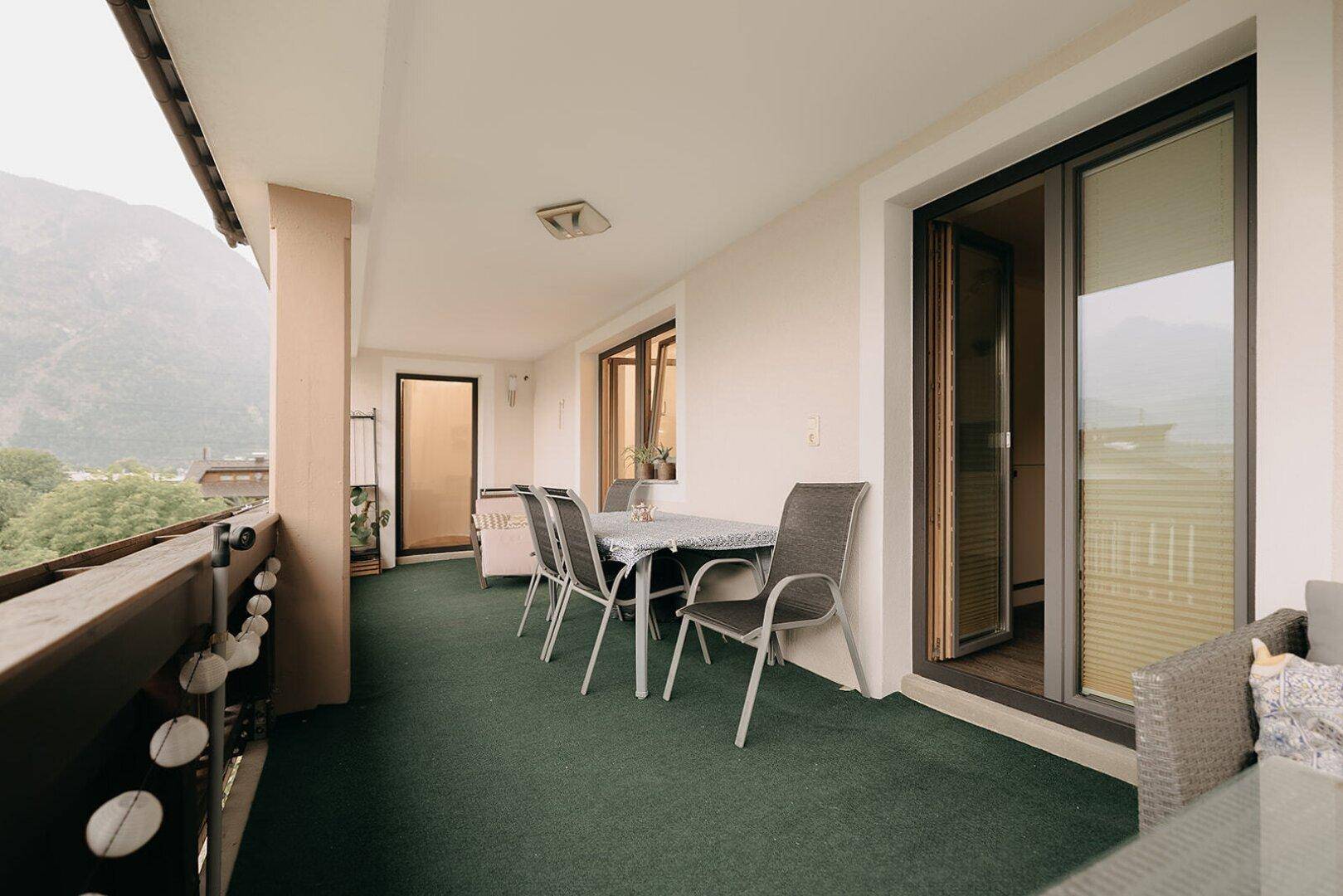 Großer Balkon mit Esstisch und Stühlen, ideal für Mahlzeiten im Freien mit Bergblick.