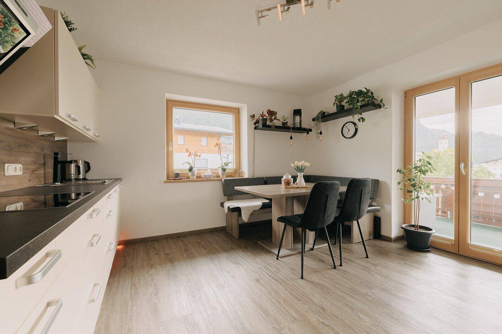 Helle Küche mit Essbereich, modernen Geräten und Zugang zum Balkon mit Bergblick.