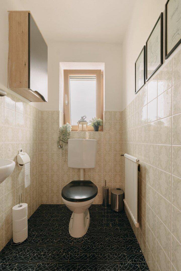 Kleines Gäste-WC mit Fenster, Toilette und Heizkörper, funktional und hell.