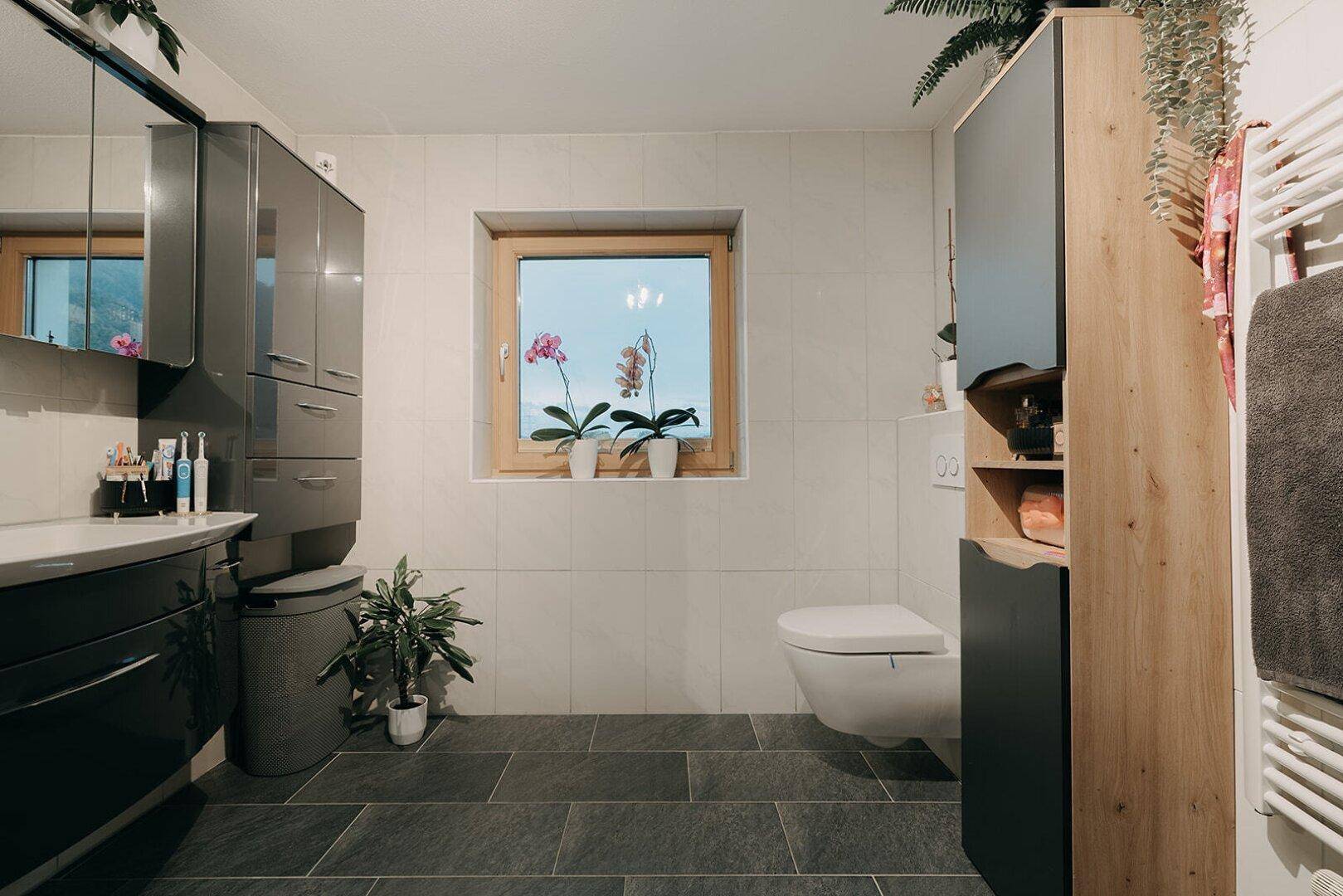 Helles Badezimmer mit Waschtisch, wandhängendem WC und beheiztem Handtuchhalter.