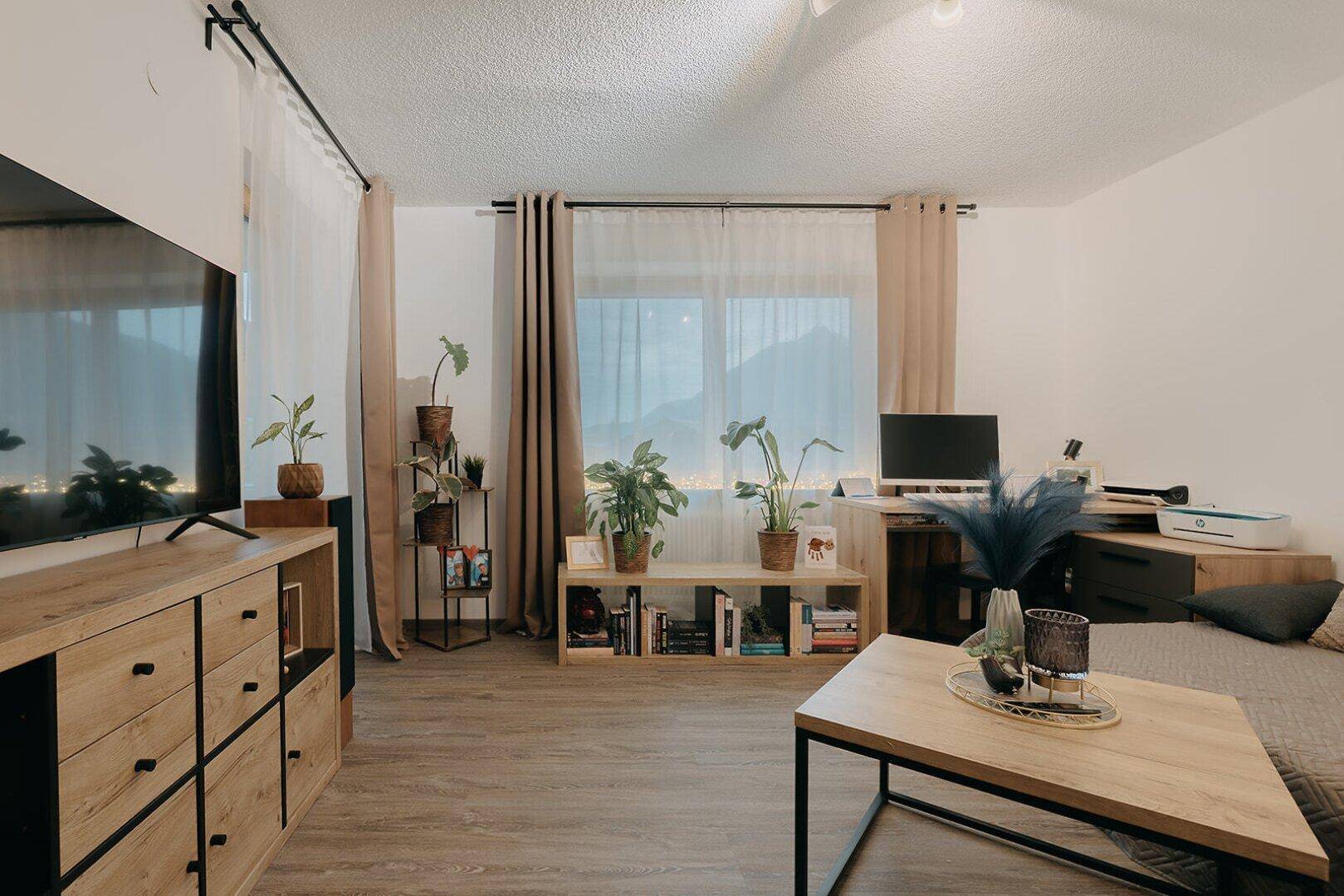 Gemütliches Wohnzimmer mit Sofa, Couchtisch und Blick auf die Berge durch das Fenster.