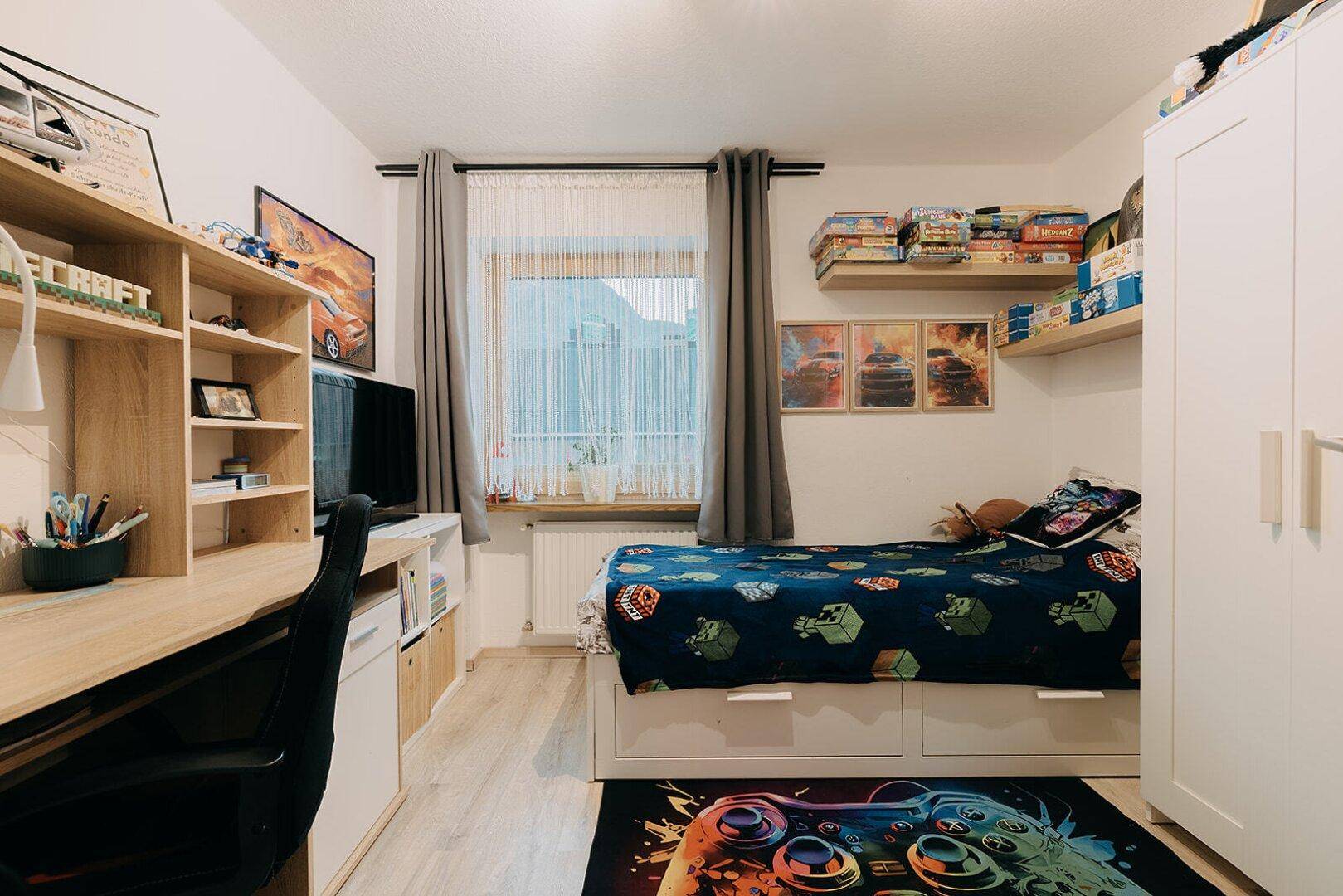Kinderzimmer mit Einzelbett, Schreibtisch und Stauraum unter dem Bett, modern eingerichtet.