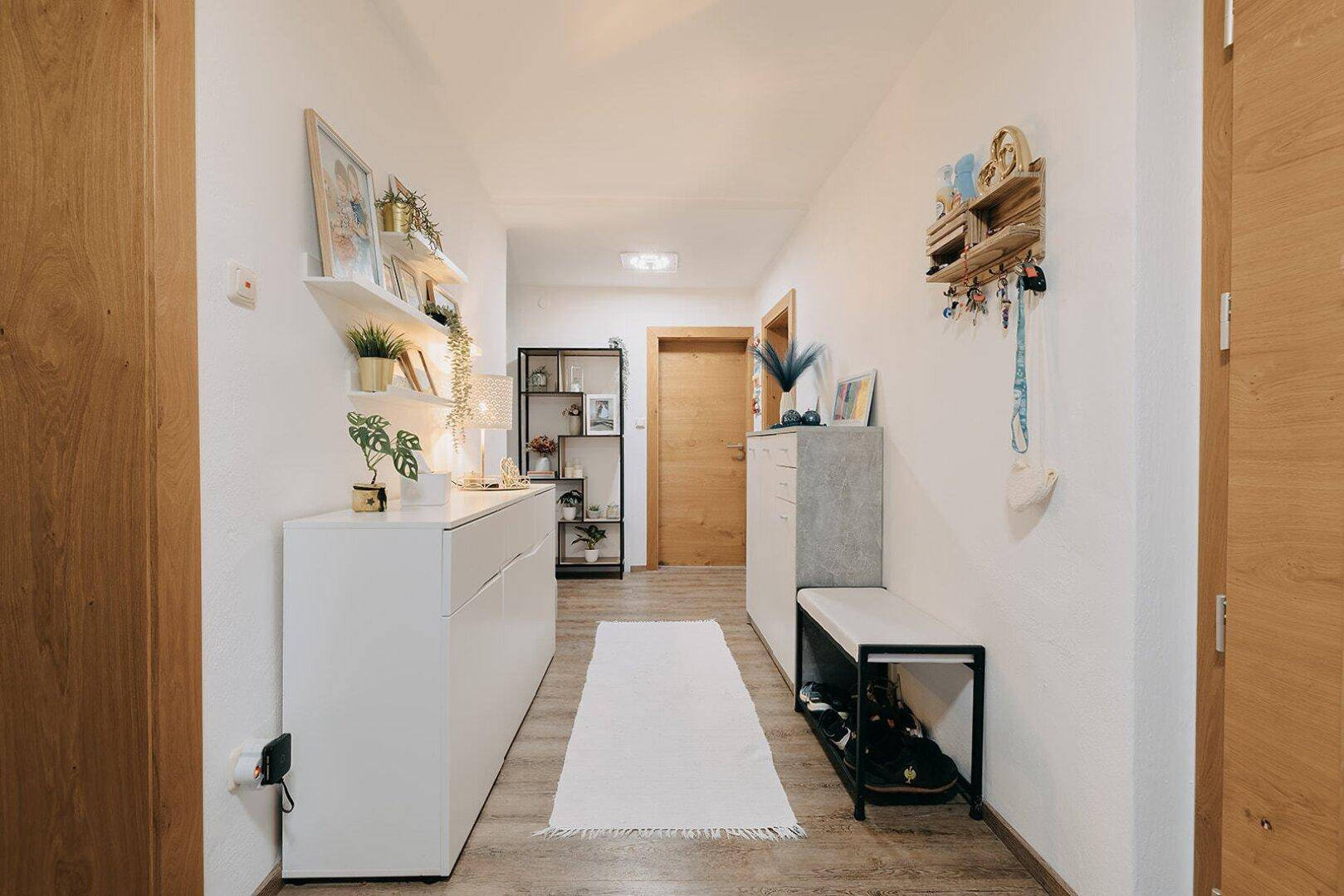 Heller Flur mit Garderobe, Schuhbank und dekorativen Regalen, einladend gestaltet.
